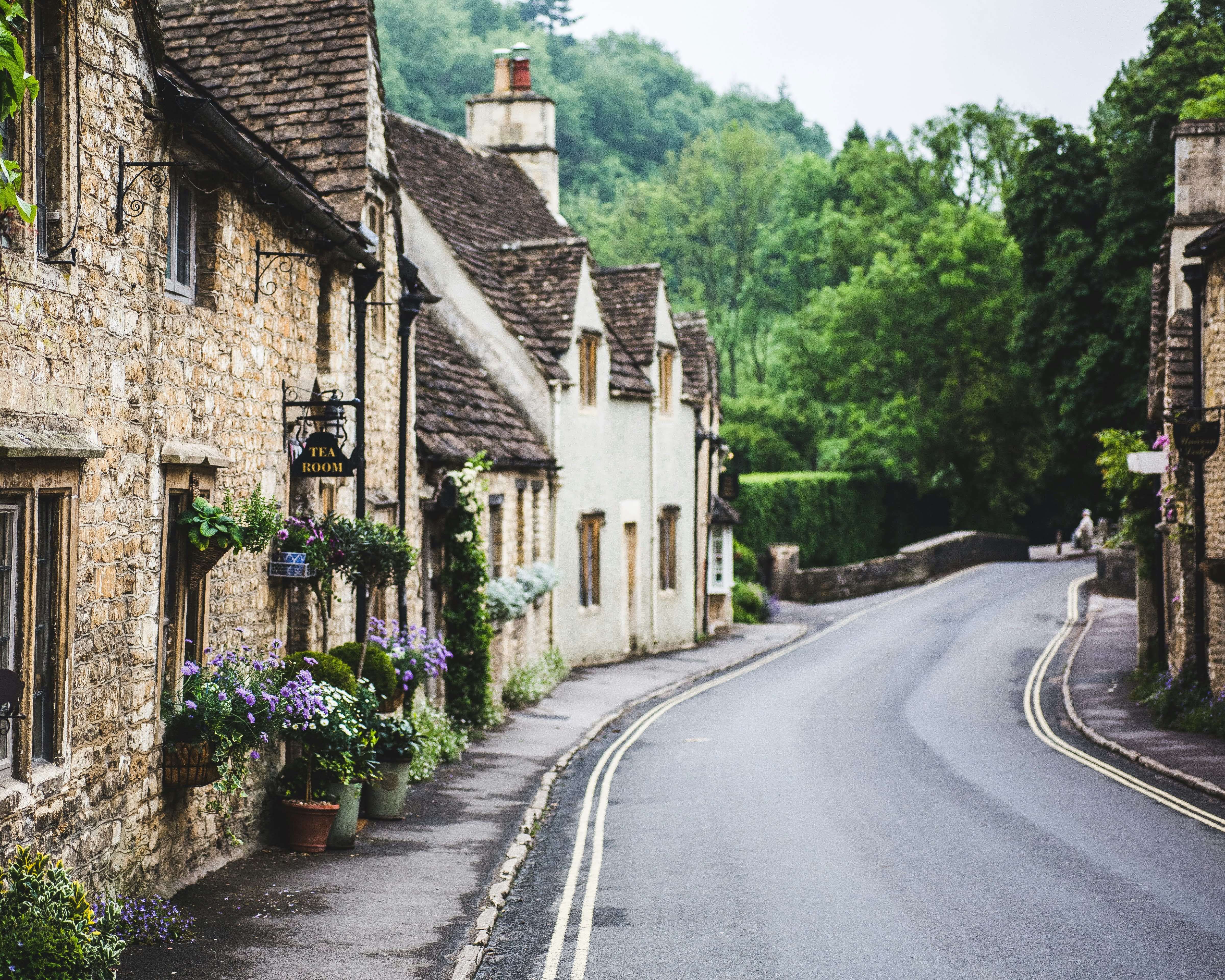 a country road through an old English village with thatched buildings