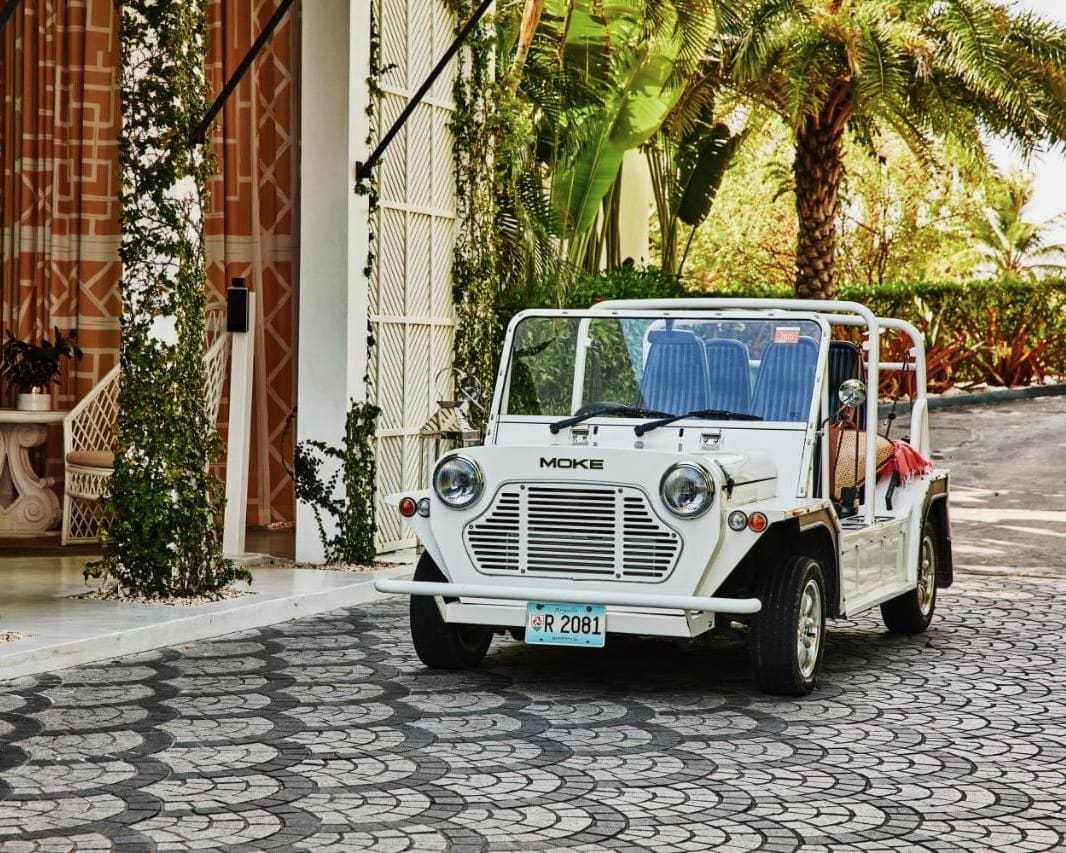 a small white moke roofless motor vehicle next to a white tropical resort