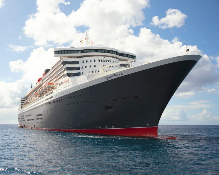 a white and black cruise ship with red bottom hull at sea under blue skies with white clouds