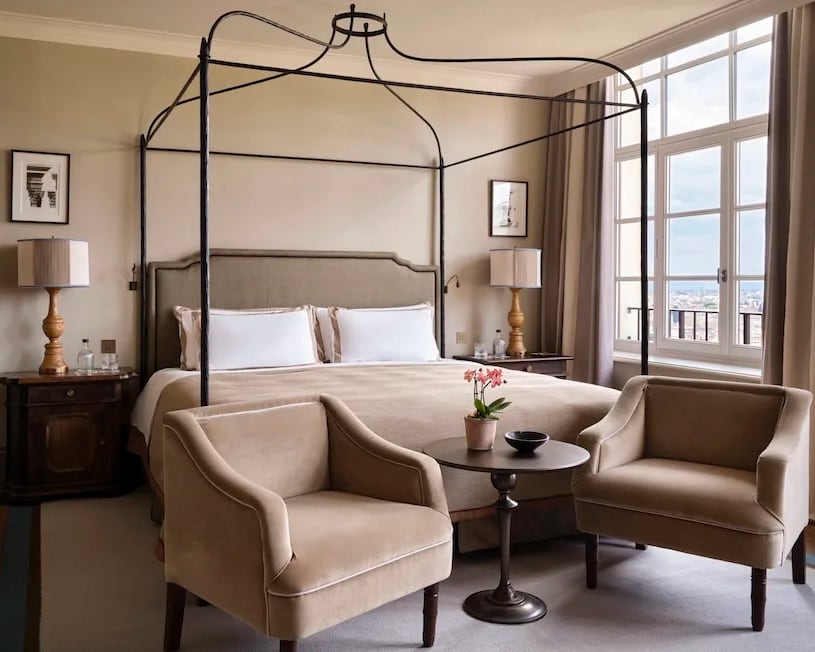 black metal four poster bed with white linens and tan decor