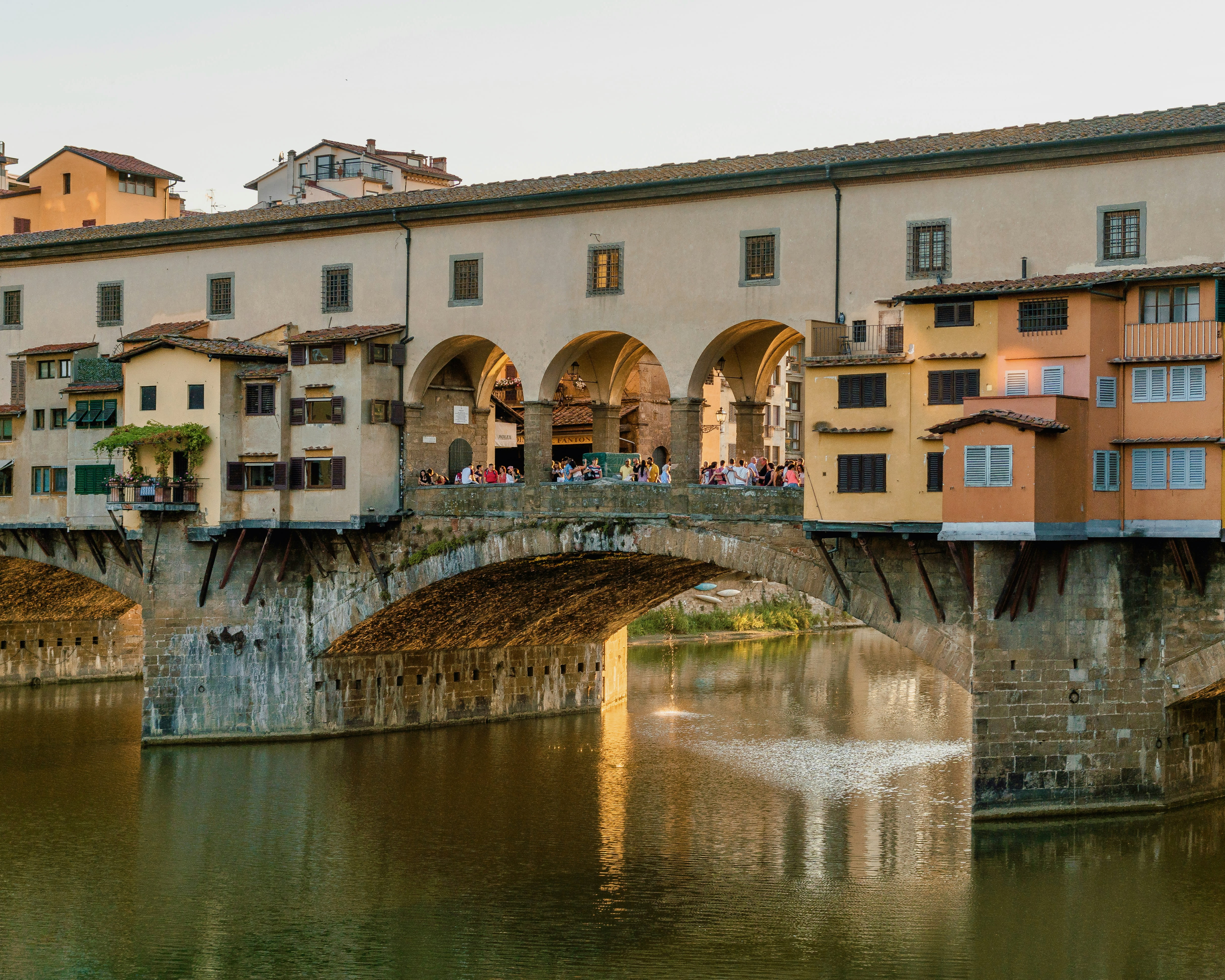 historic stone bridge over a river with multicolored homes on top of it during day