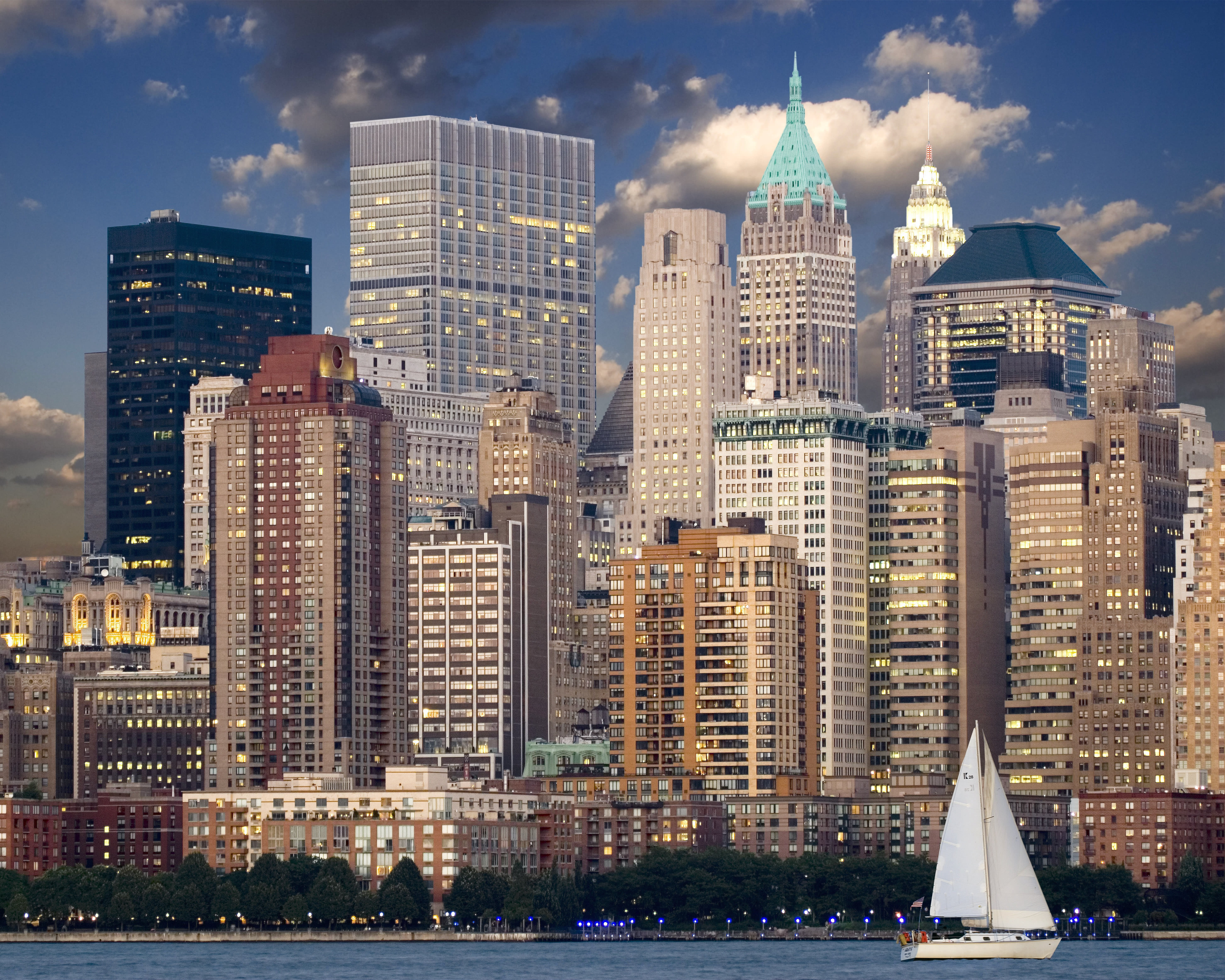 skyline of skyscrapers along water with a sailboat in the foreground