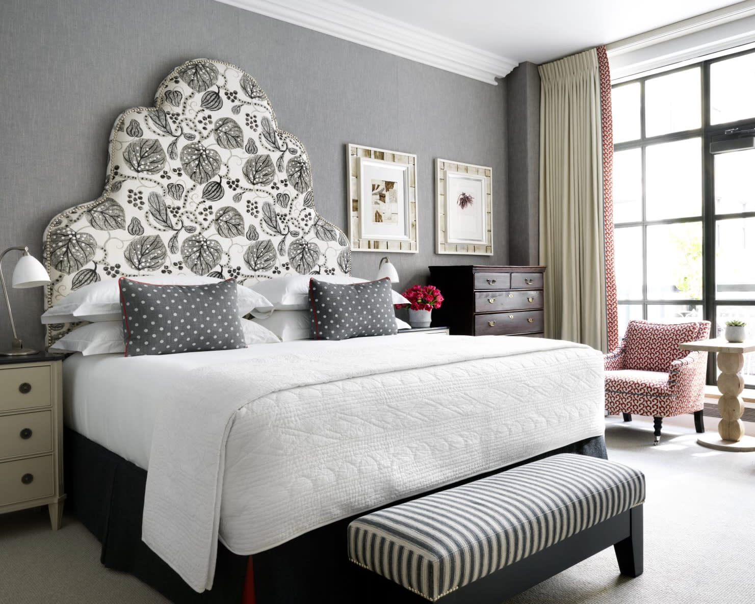 white hotel bed with patterned fabric headboard beside windows