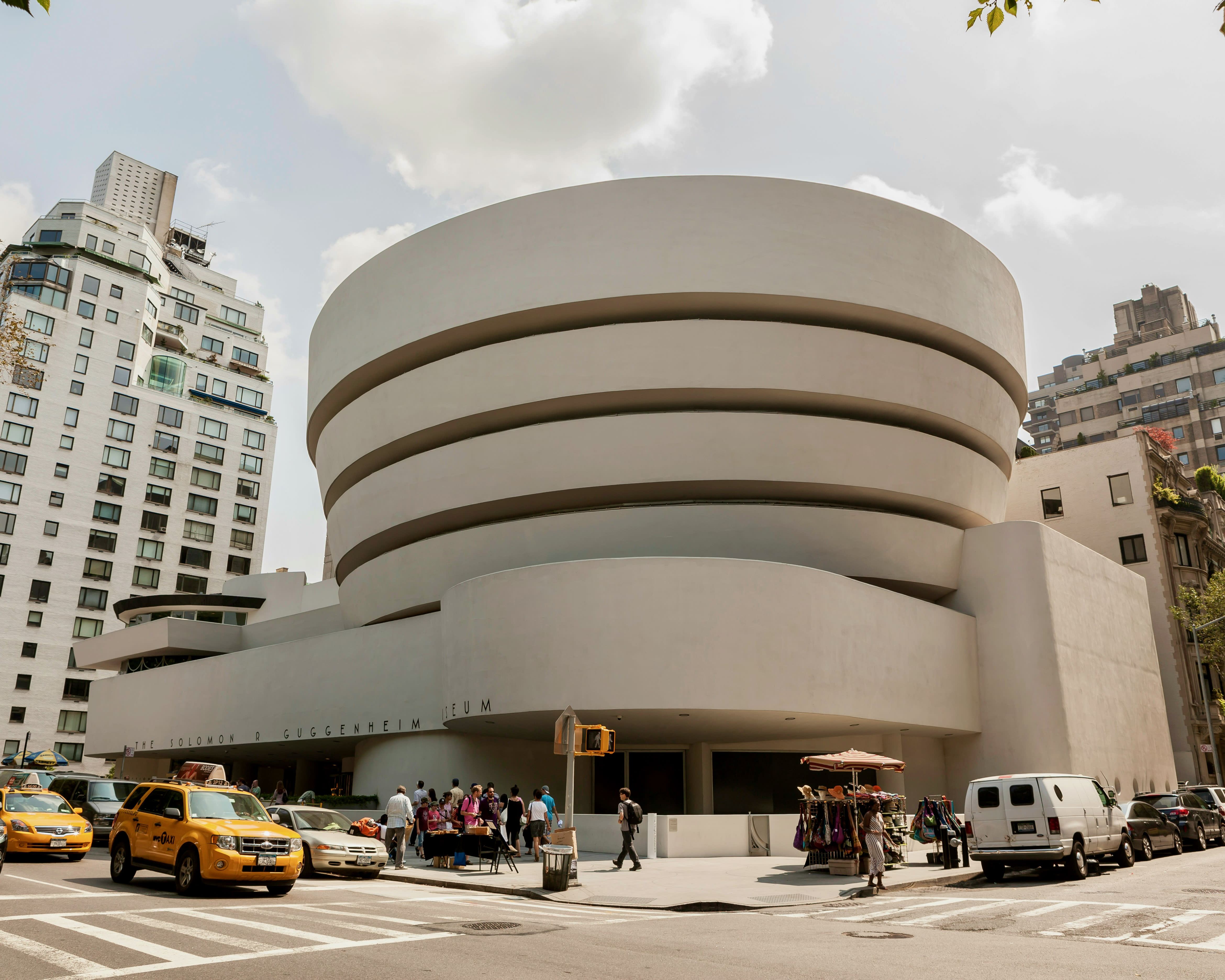 rounded white modern building with street traffic in front