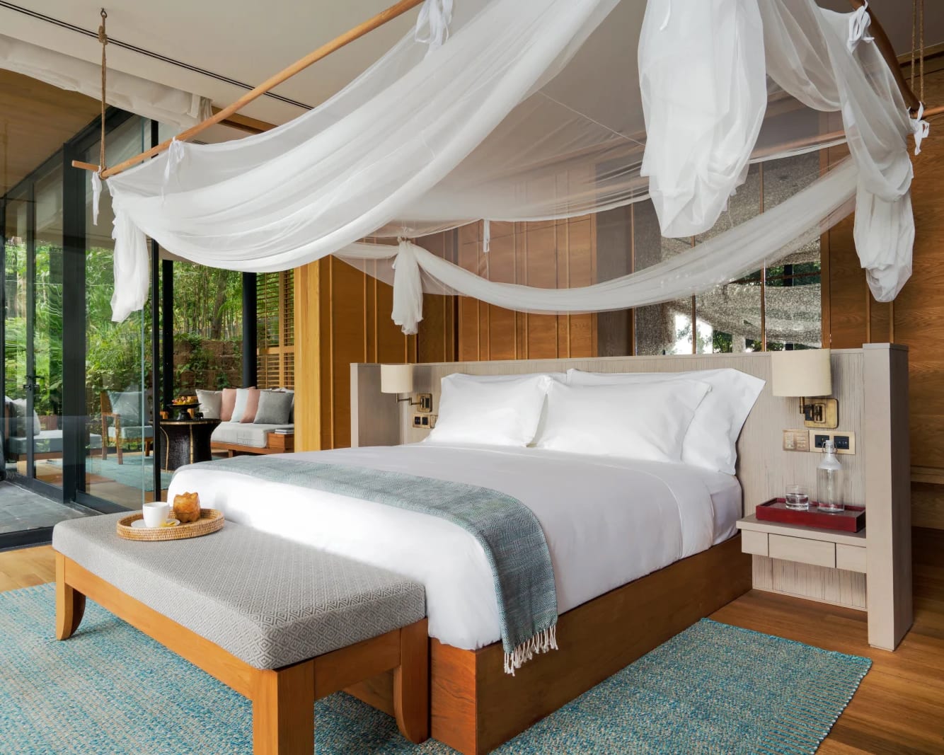 tropical wood hotel room with white sheets and white net above the bed