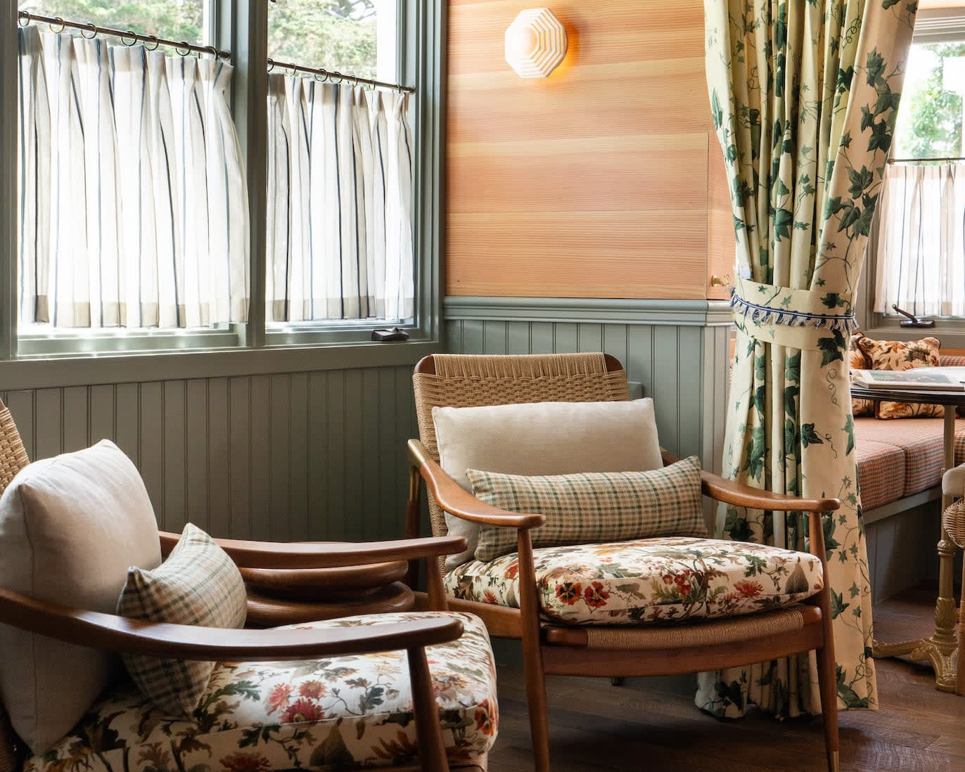mid century modern chairs next to a window and patterned curtain