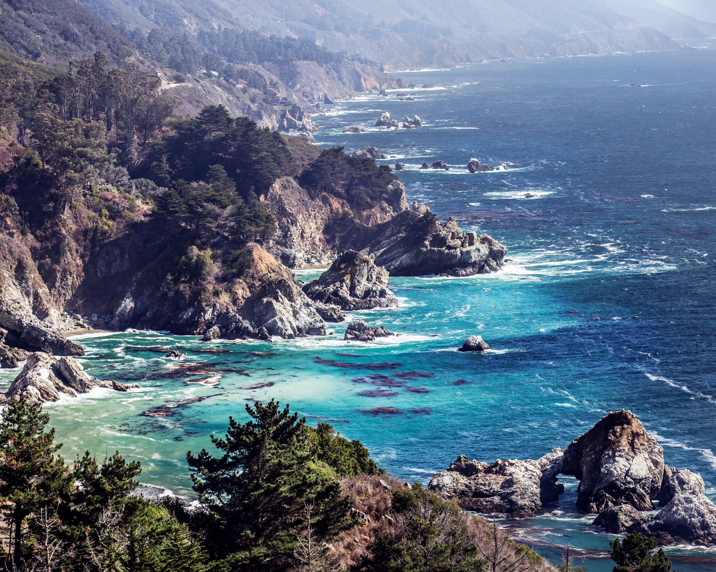 rocky mountain cliffs descending into blue ocean waters