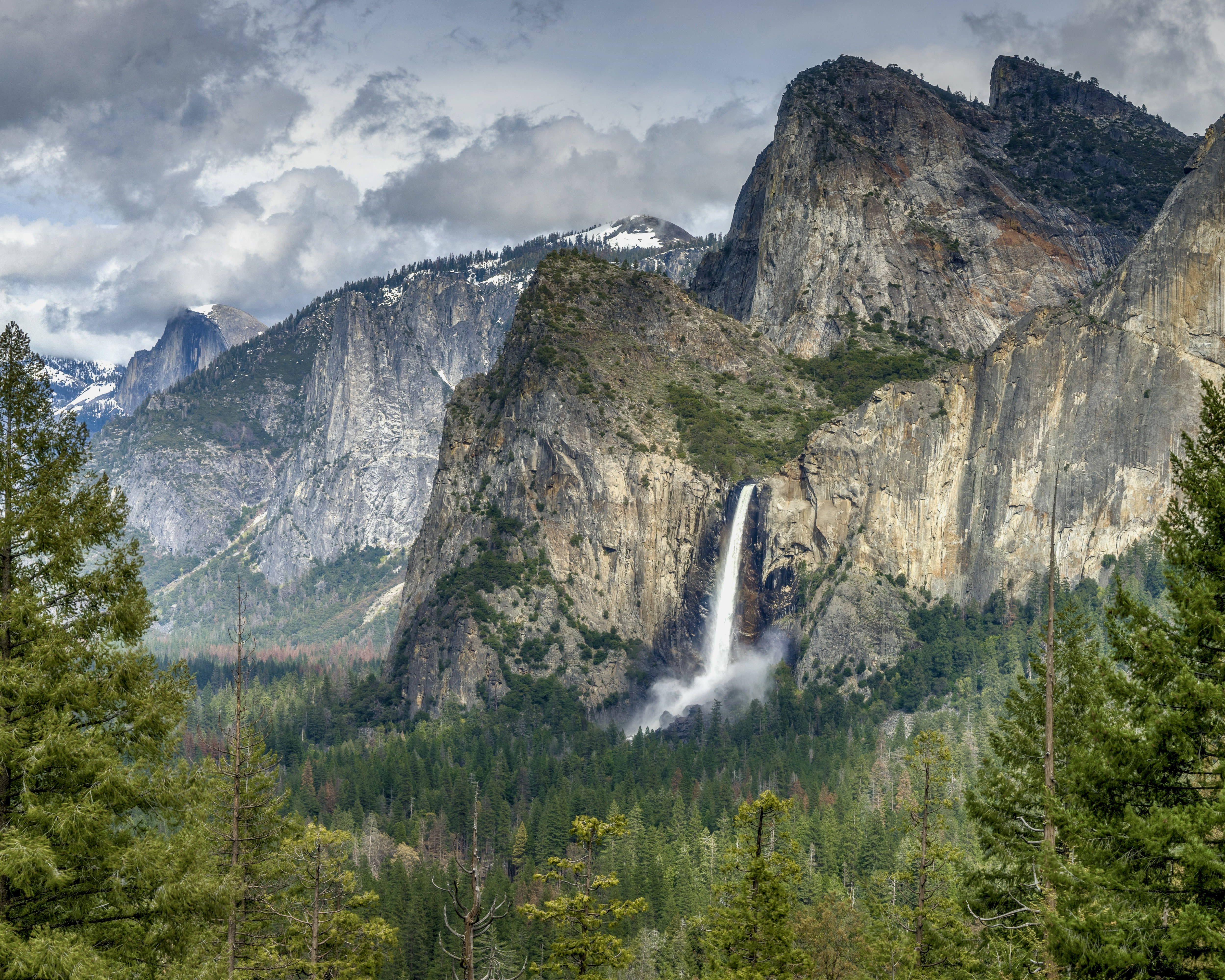 landscape of green trees with mountain in the background and waterfall descending into the valley