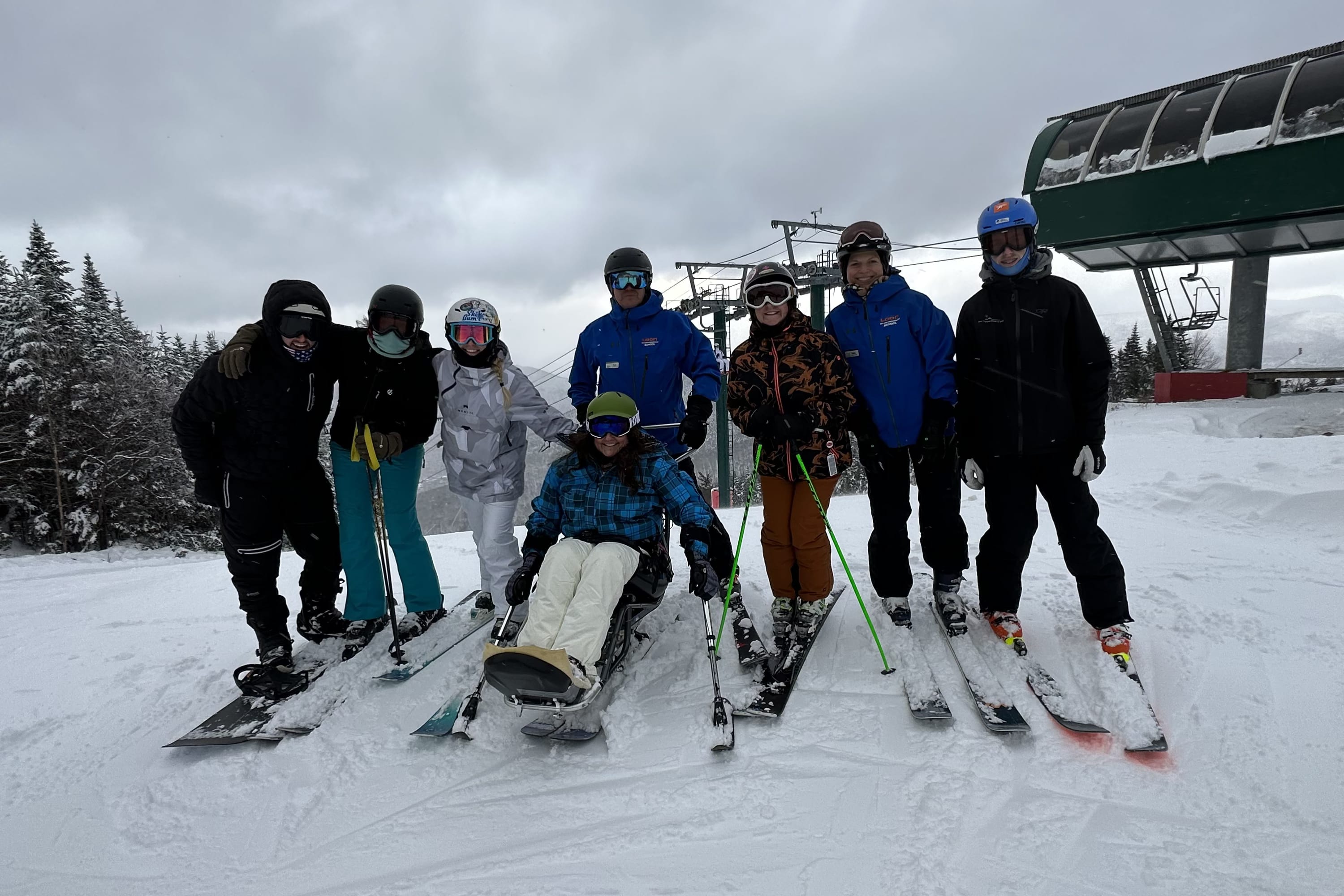 a group of people in ski gear smile at the top of the chair lift