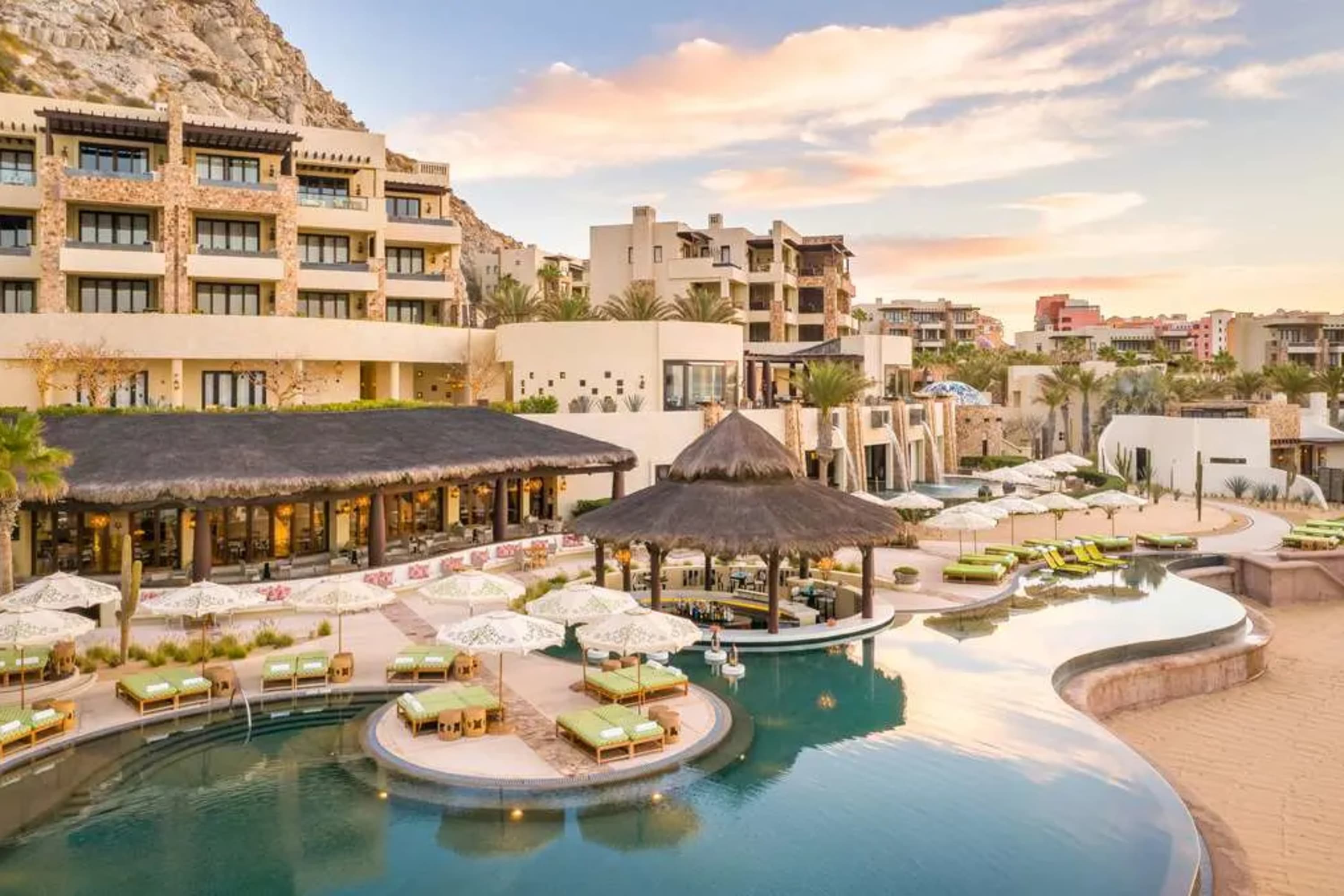 Aerial view of a chic pool area with a swim-up bar. In the background, you can see the hotel and each unit's private balcony, all before a rocky mountain