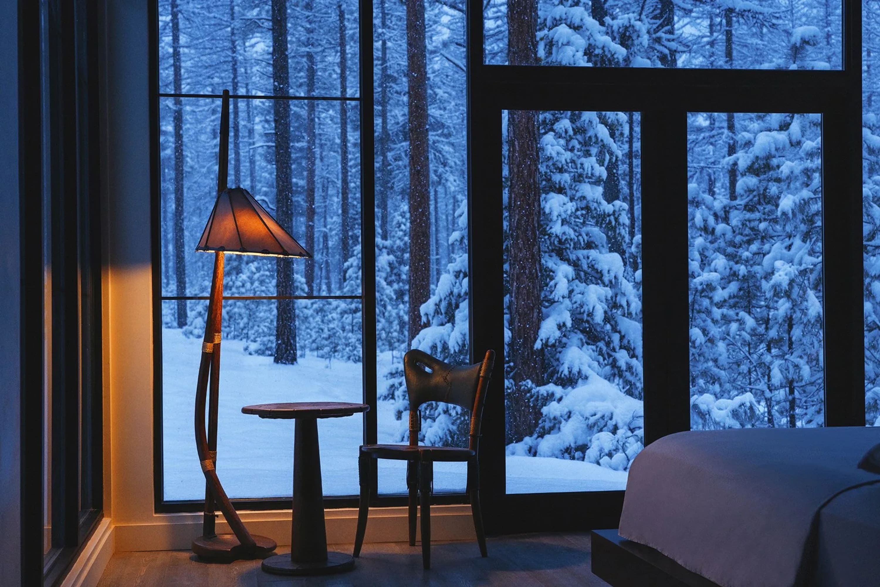 Sleek and cozy contemporary decor offer a sharp departure from rustic themes, and floor-to-ceiling windows reveal a snowy forest