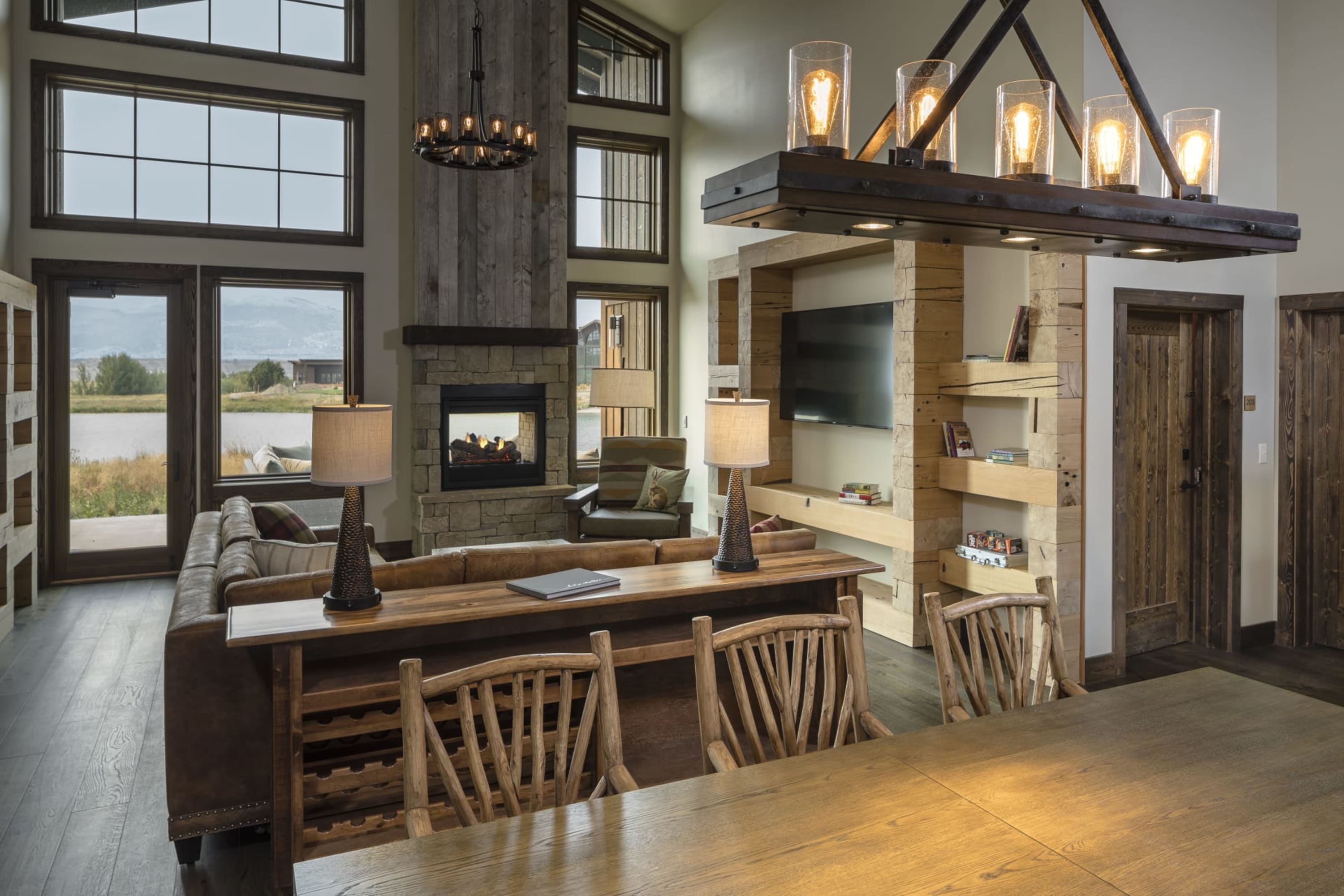 Rustic influences are evident in otherwise contemporary decor - mountain chic - in a large living room area with a series of rising windows revealing the Montana landscape