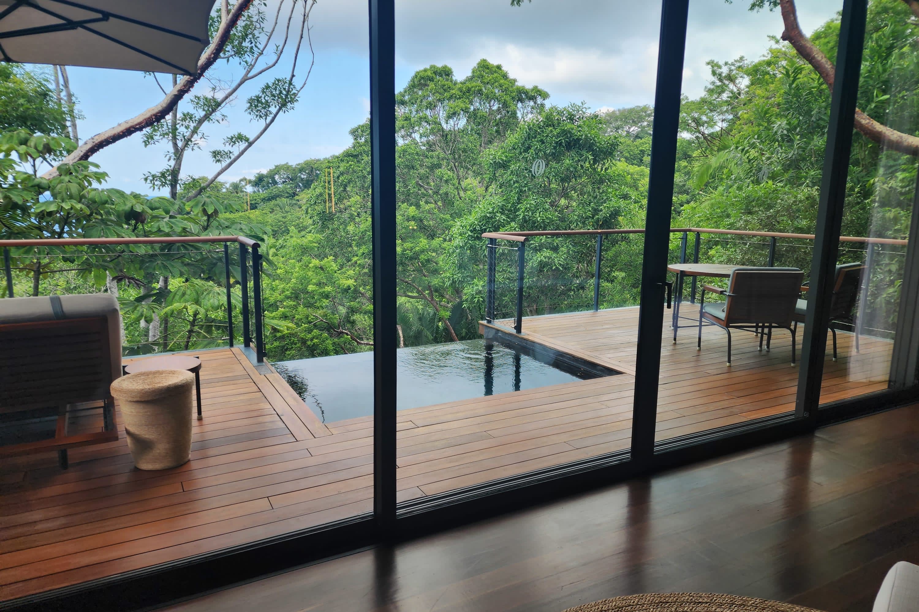A contemporary hardwood balcony with chic furnishings and a plunge-pool-size infinity pool overlooking Puerto Vallarta jungle