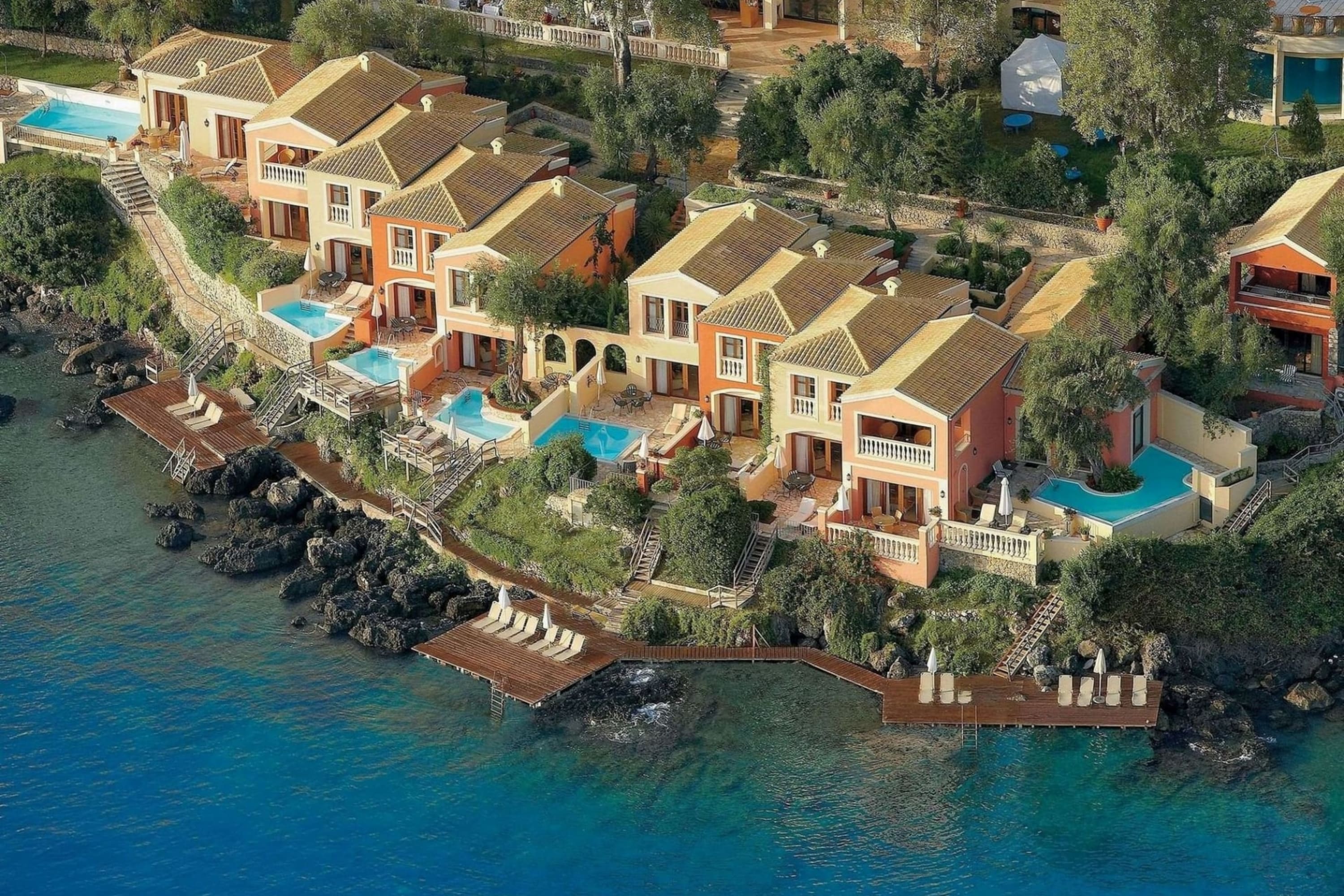 Townhome-like units line Corfu's rocky shoreline, with hardwood patios extending out to the sapphire water
