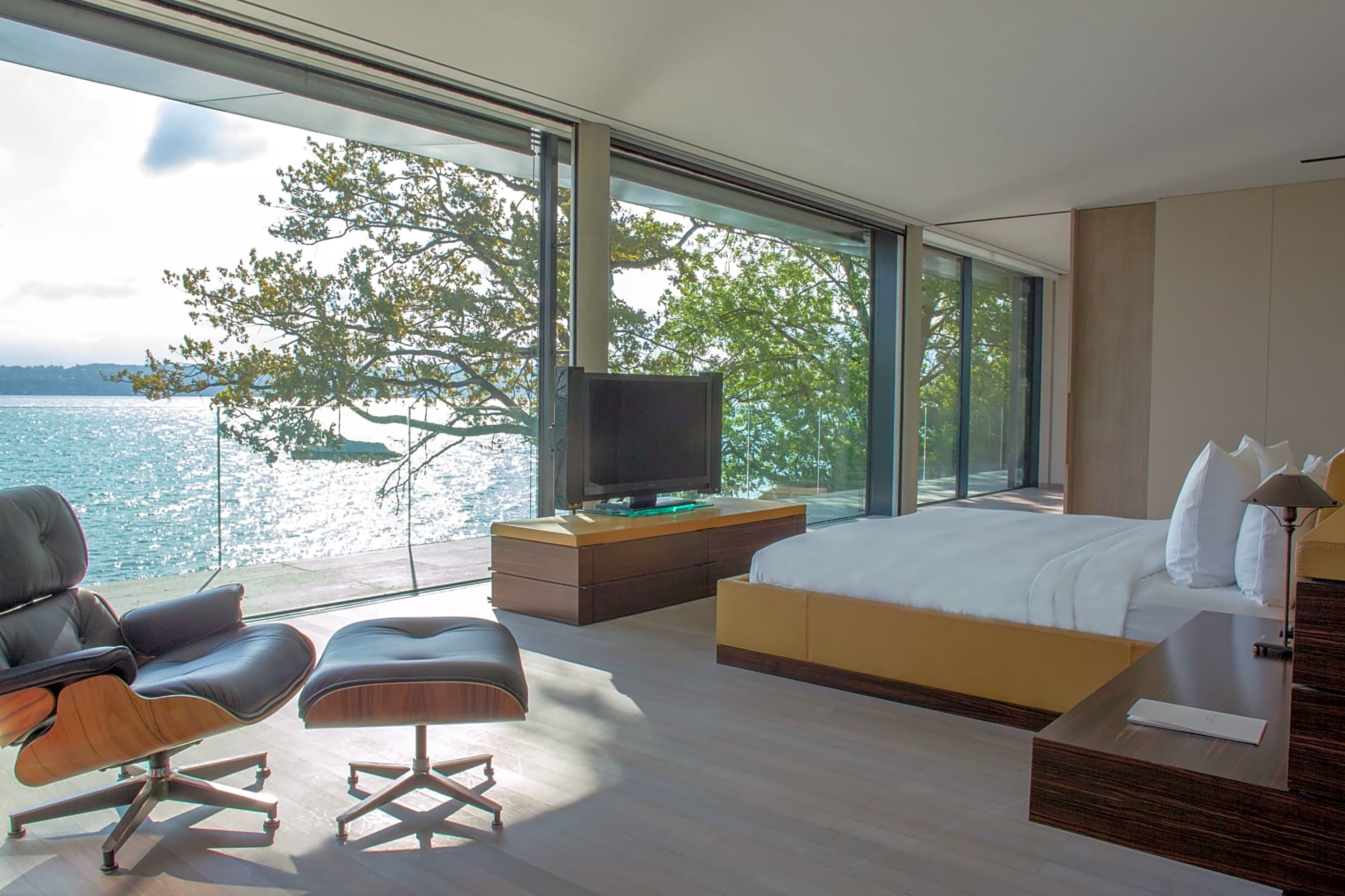 A chic, spacious room with floor-to-ceiling windows revealing a panoramic view of Lake Geneva, Switzerland