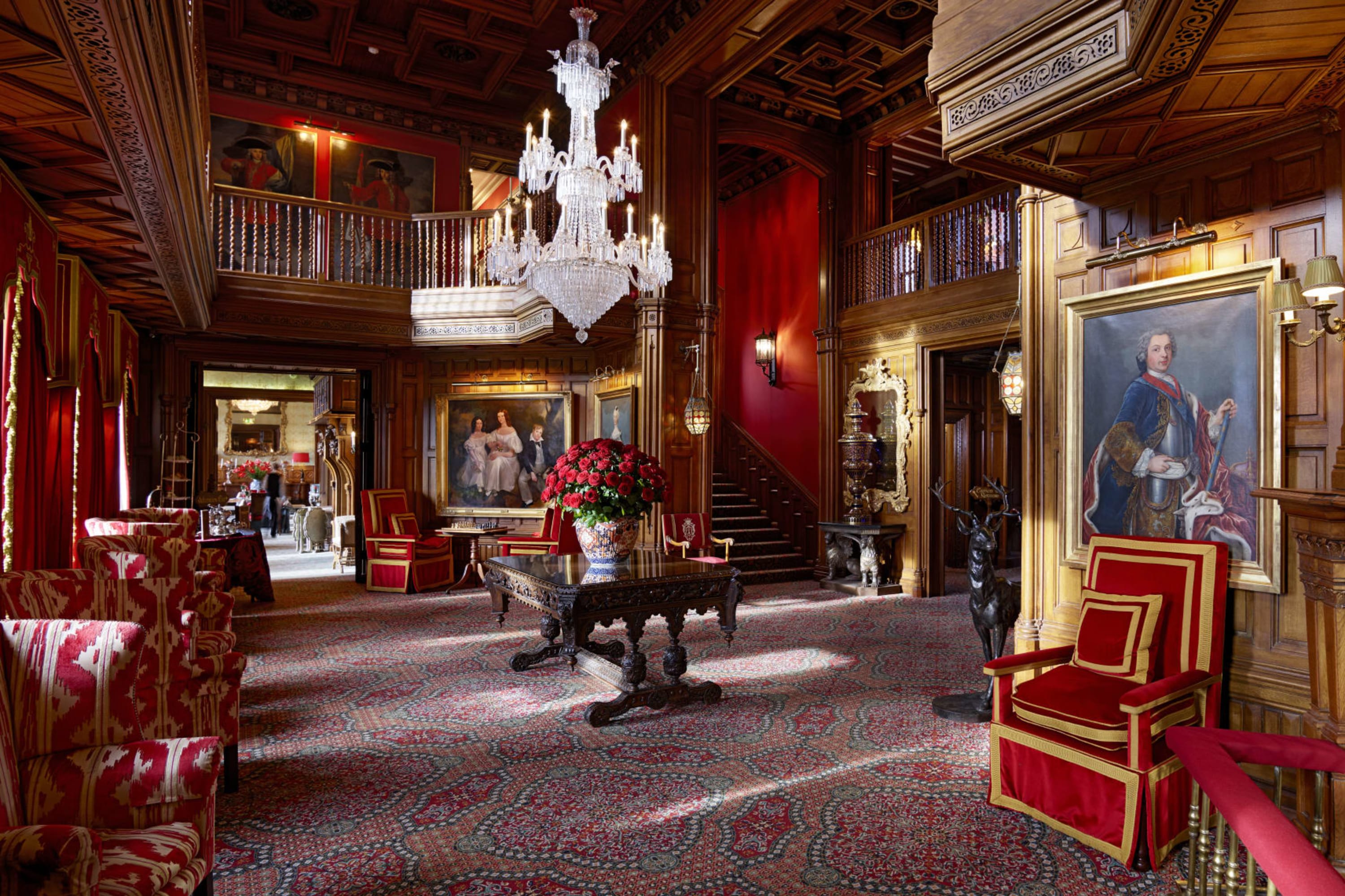 A deep-red and gold color palette permeates a moody and elegant Old World estate interior