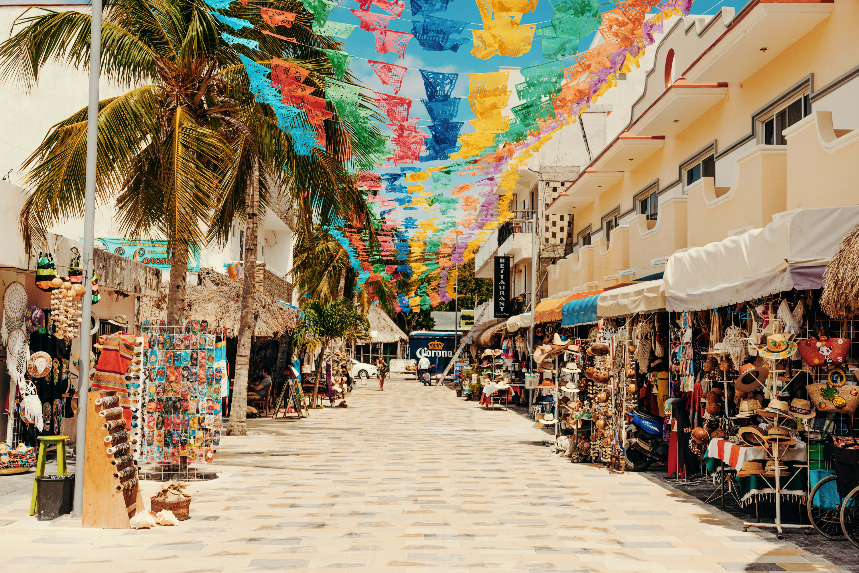 An open street market with colorful streamers strung up in lieu of an awning