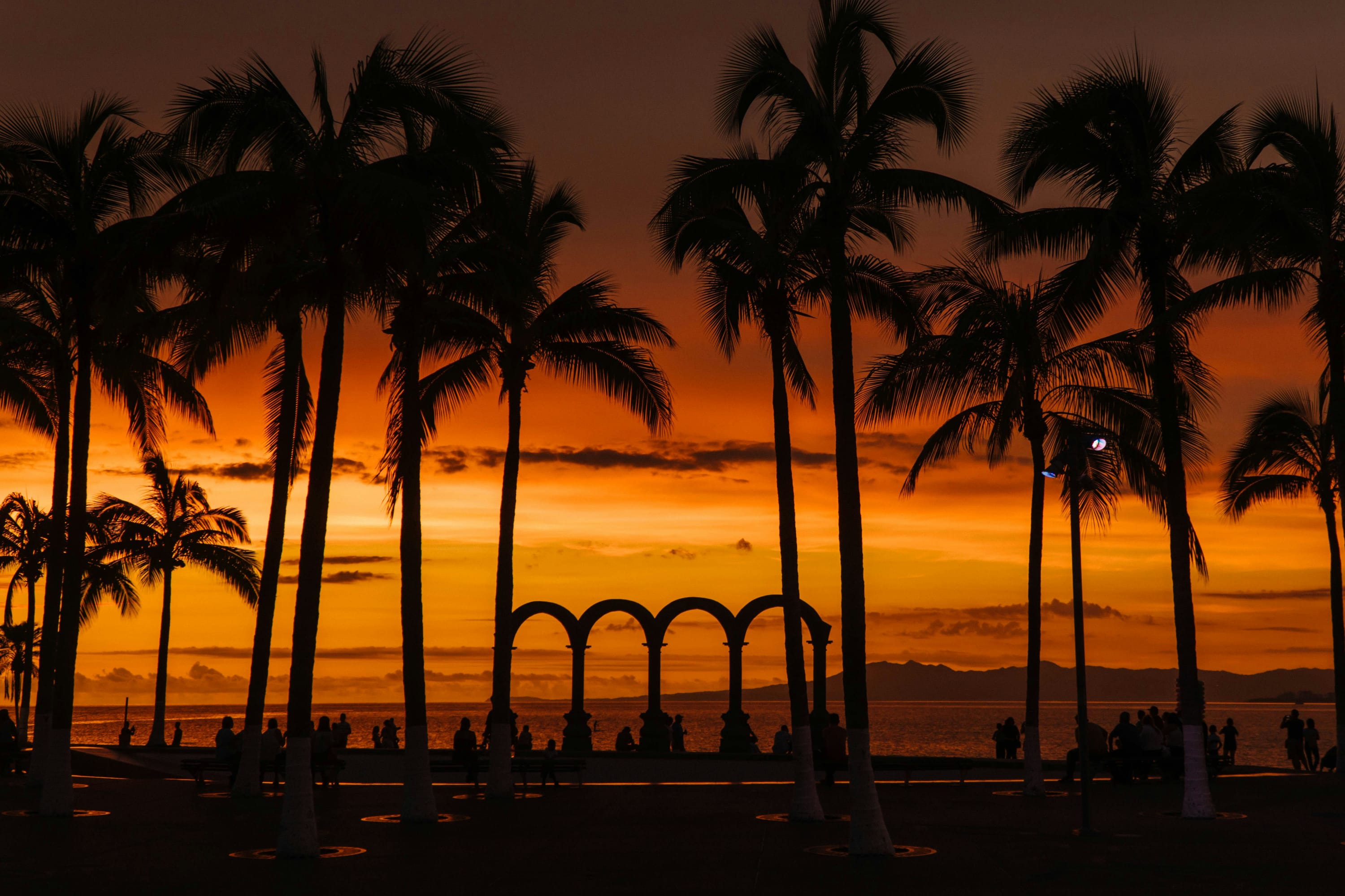 Silhouettes of palm trees and the Malecon's Los Arcos sculpture