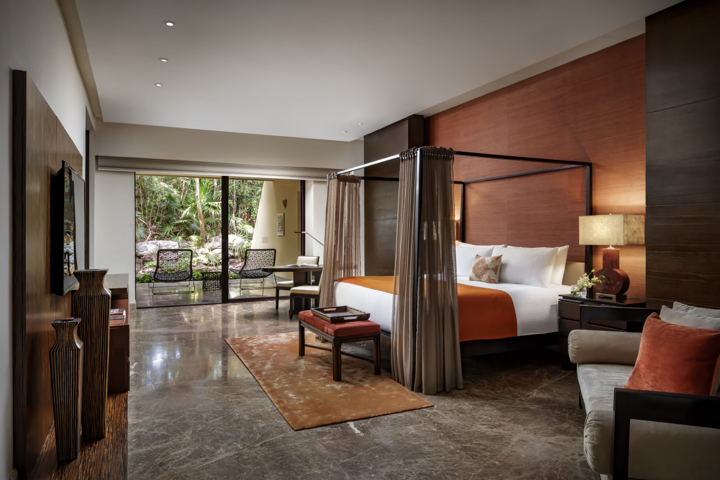 A luxe room with marble floors, an expensive rug, vibey furnishings, moody lighting and a private patio
