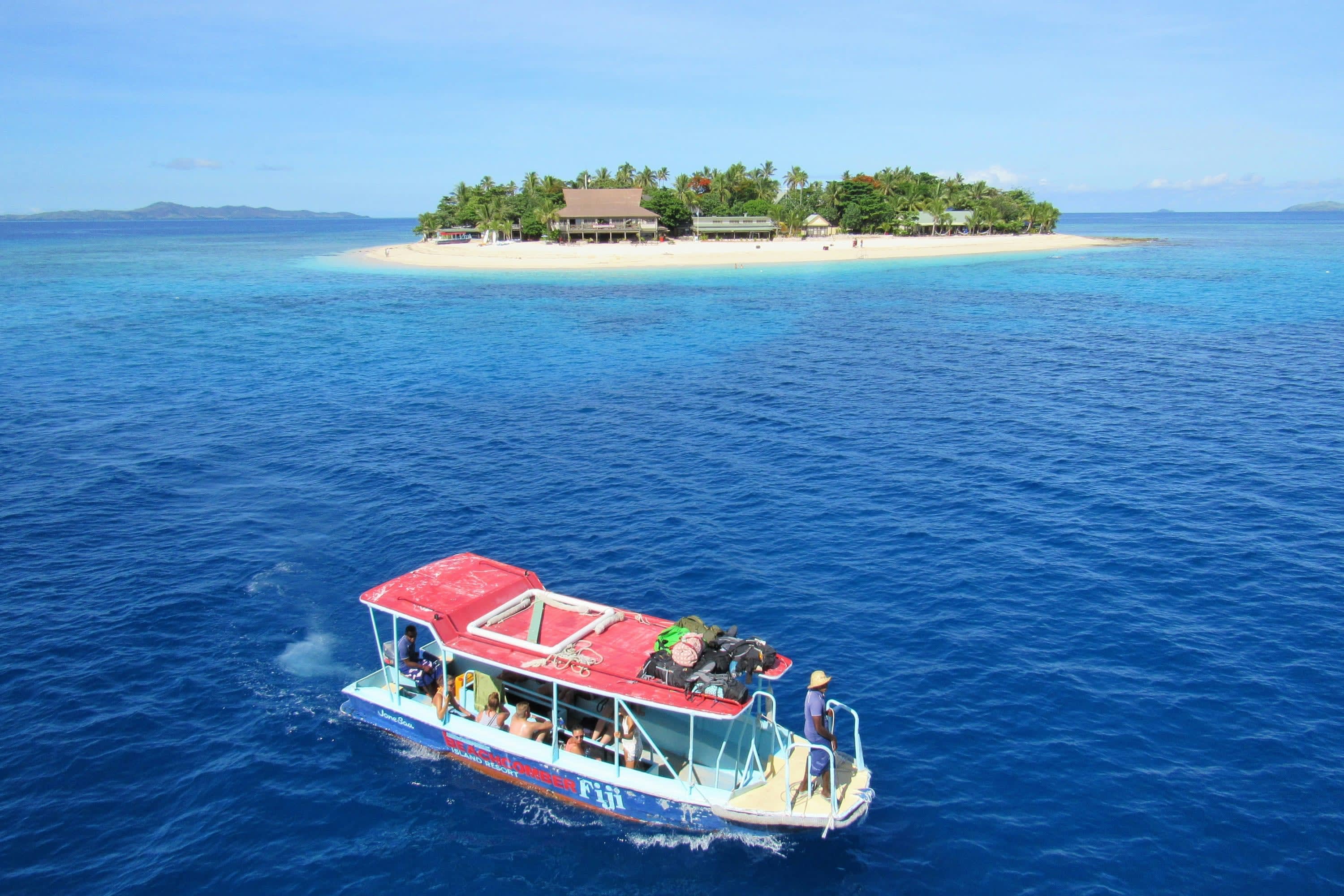 A small tour boat ferries passengers around a small island in Fiji