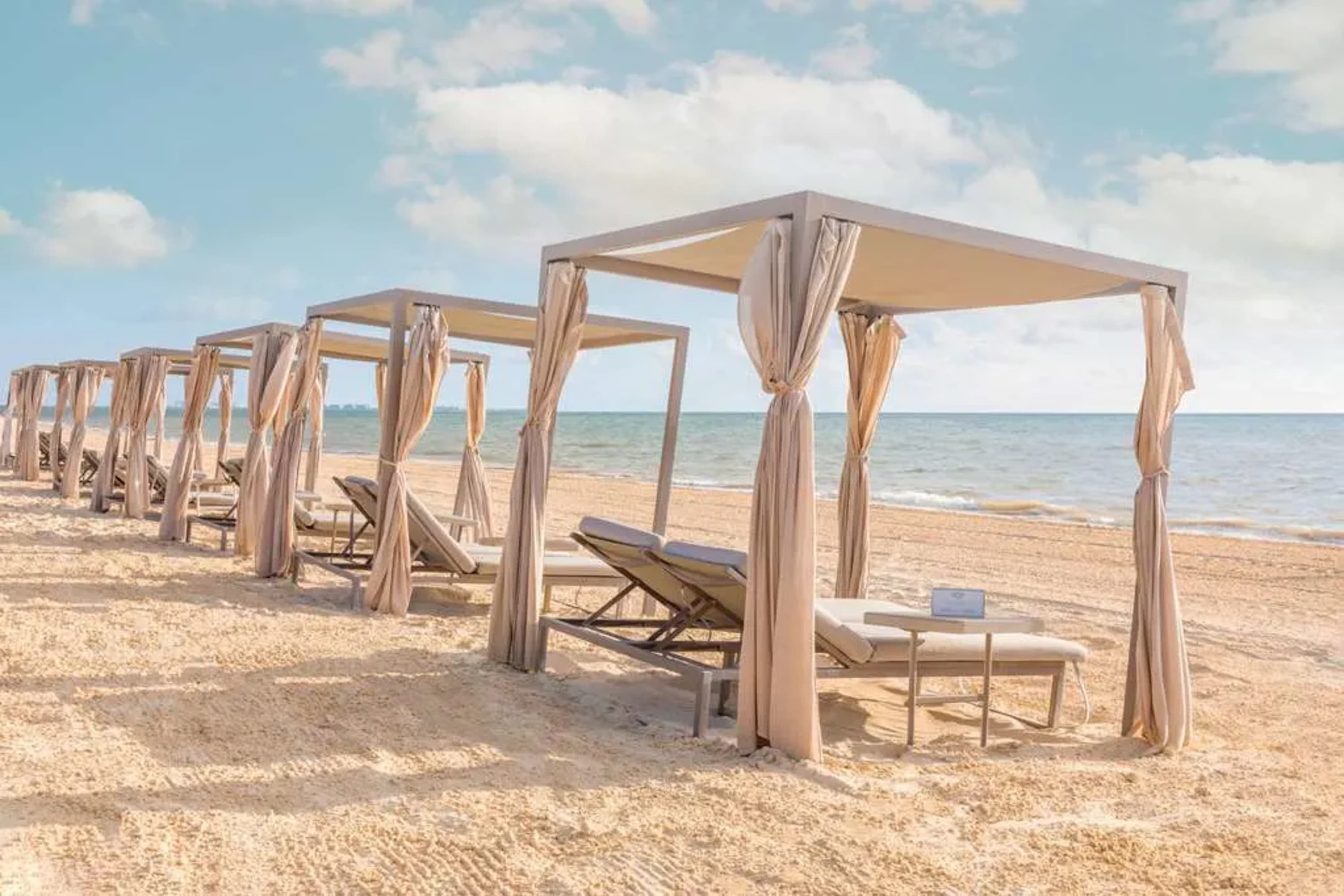 A series of luxe, private beach tents on a white-sand beach