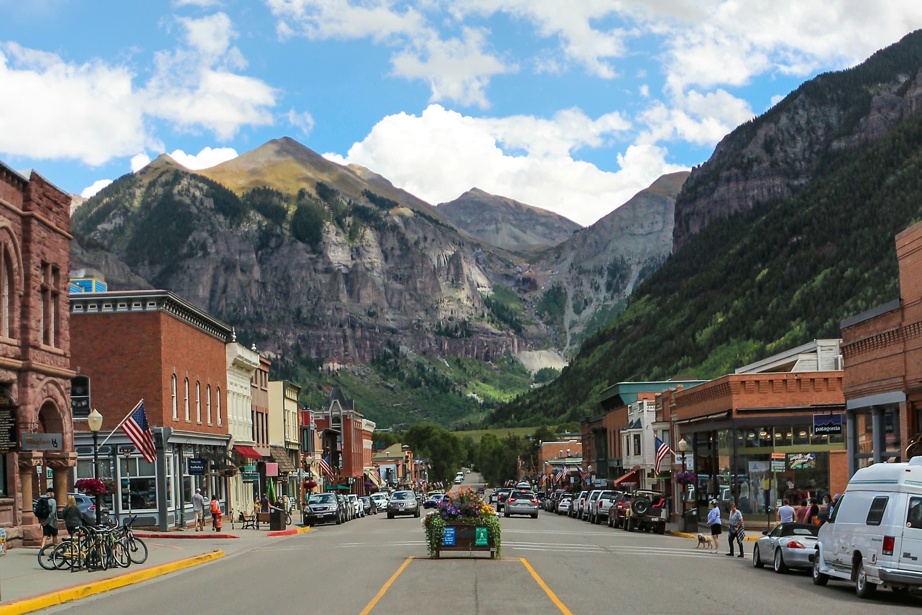 Downtown Telluride street with people walking along shops and a flower cart in the center