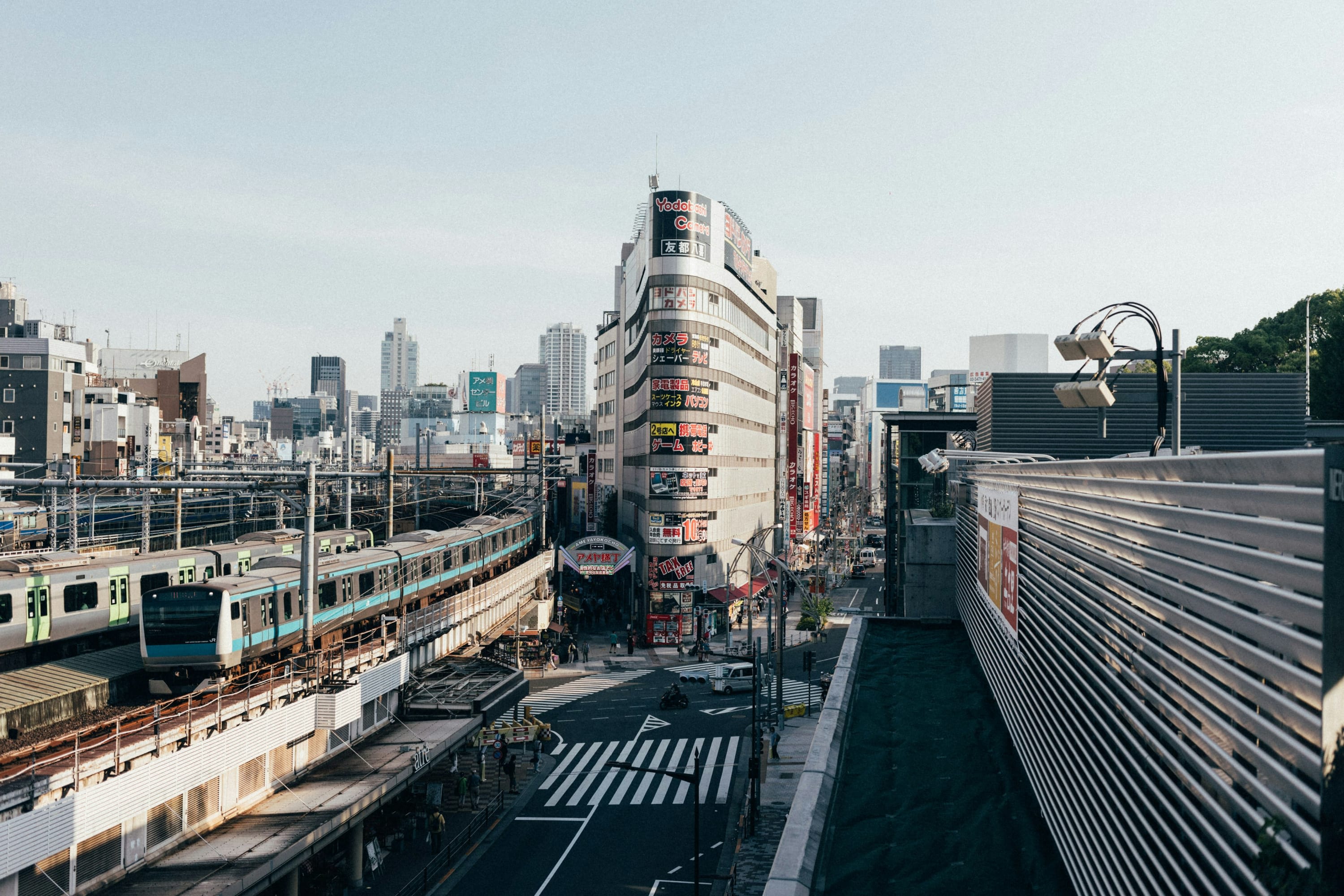 A heavily urban street with a metro rolling by and Tokyo's downtown skyline in the distance