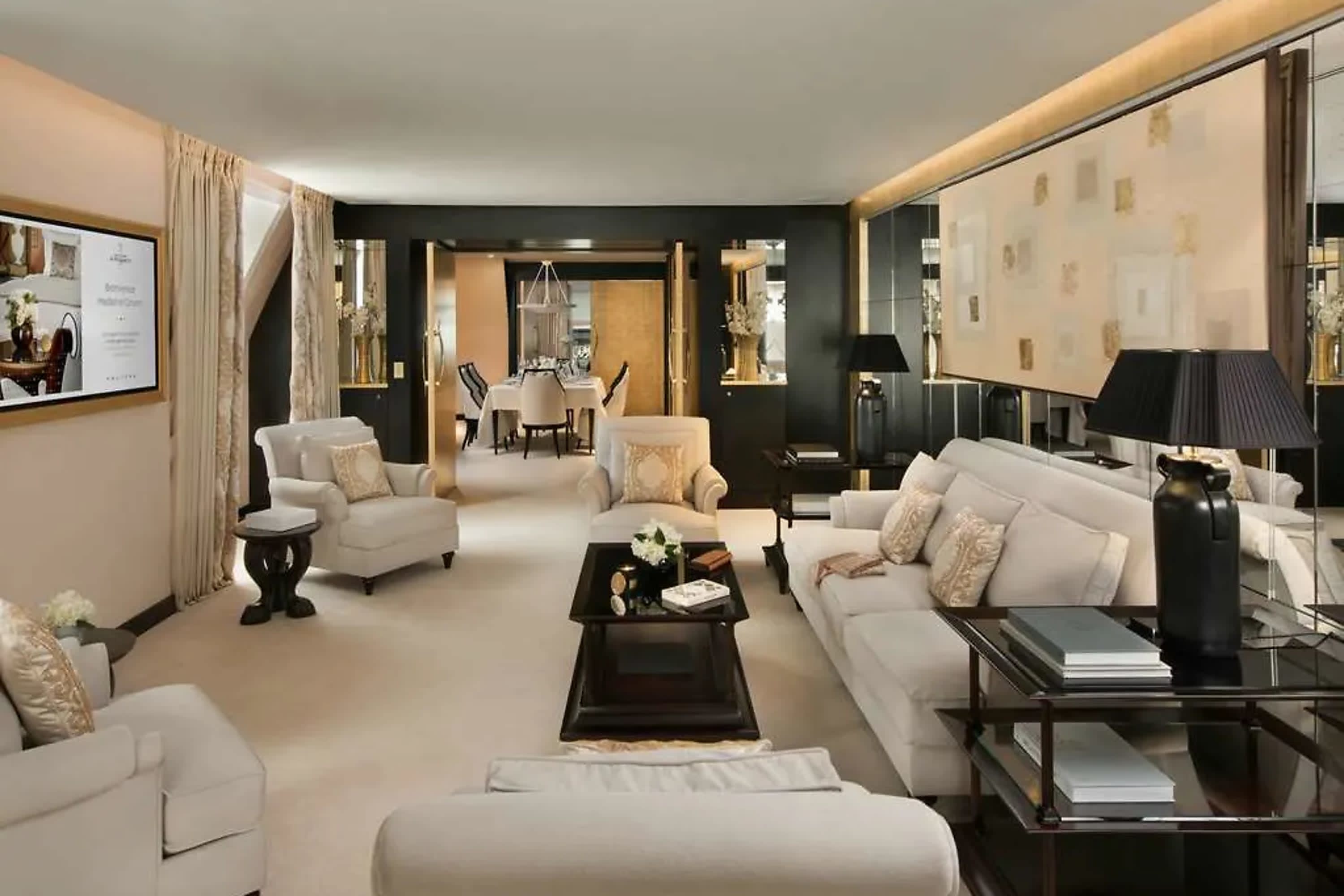 Elegant suite living room area with high-end furnishings and decor. A small, white floral arrangement sits on the coffee table and eclectic art hangs on the walls