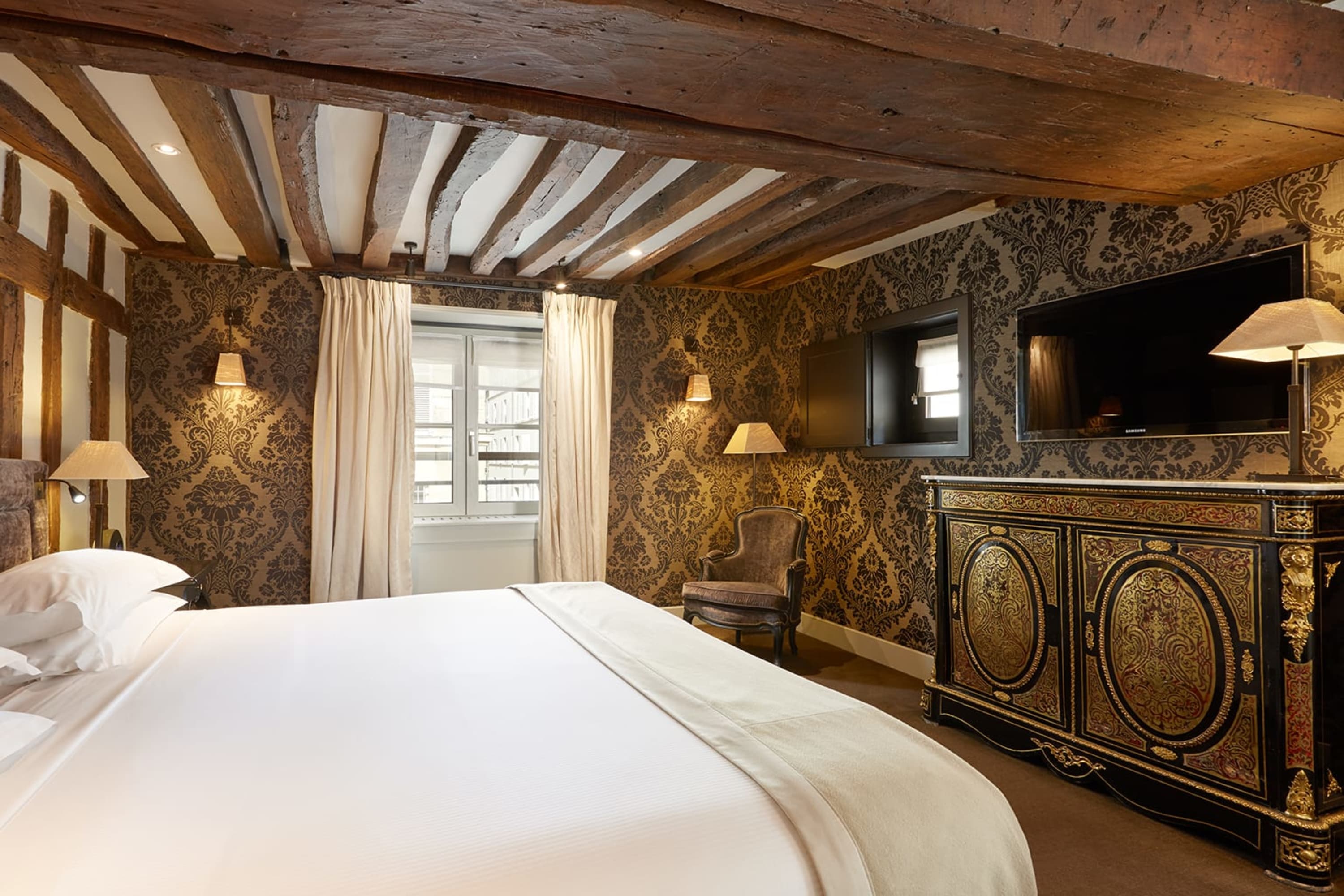 Gilded Art Deco decor is accented with natural wood beams and paneling in a spacious, homey hotel room