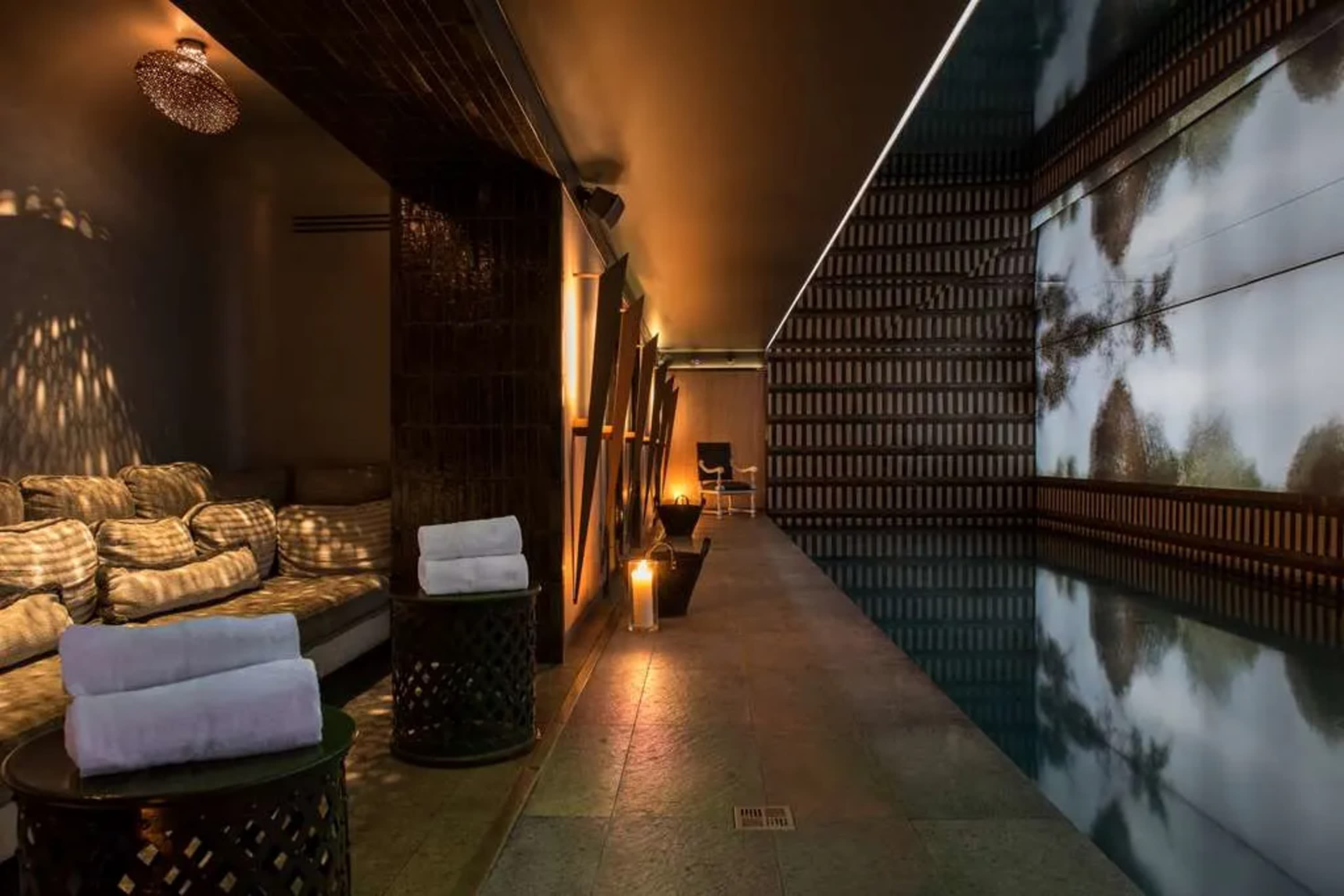 A moody, chic pool area with dim gold lighting and an artful mural on the opposing wall