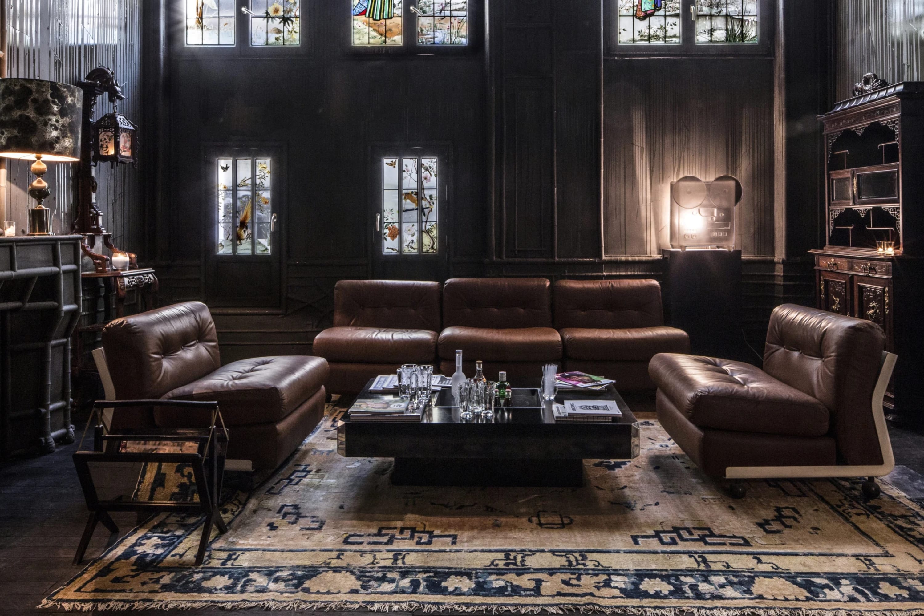 A moody lounge area with colorful stained glass windows on the opposing side