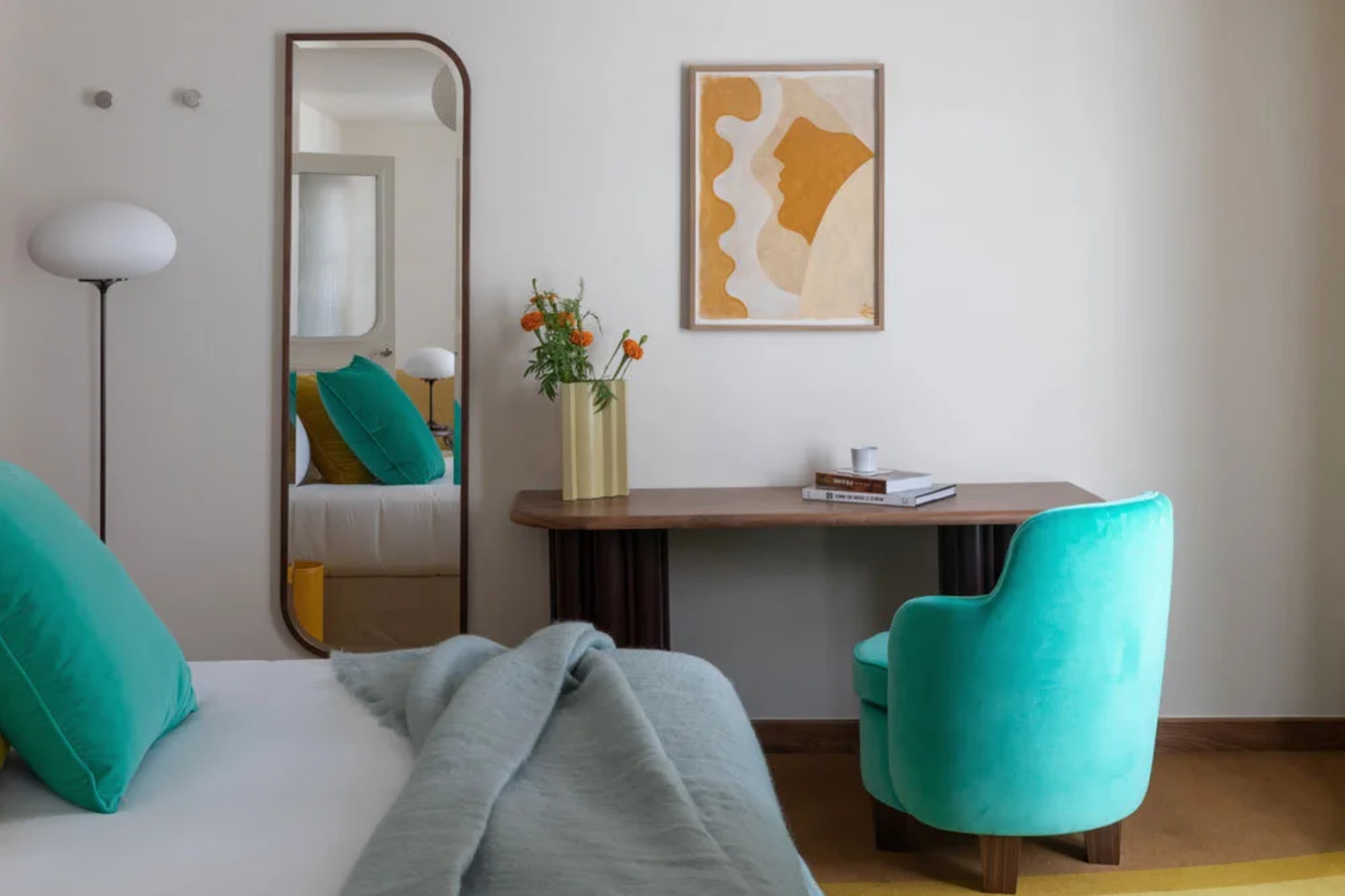 Simple but stylish hotel room with bold, turquoise pops of color and eclectic abstract art