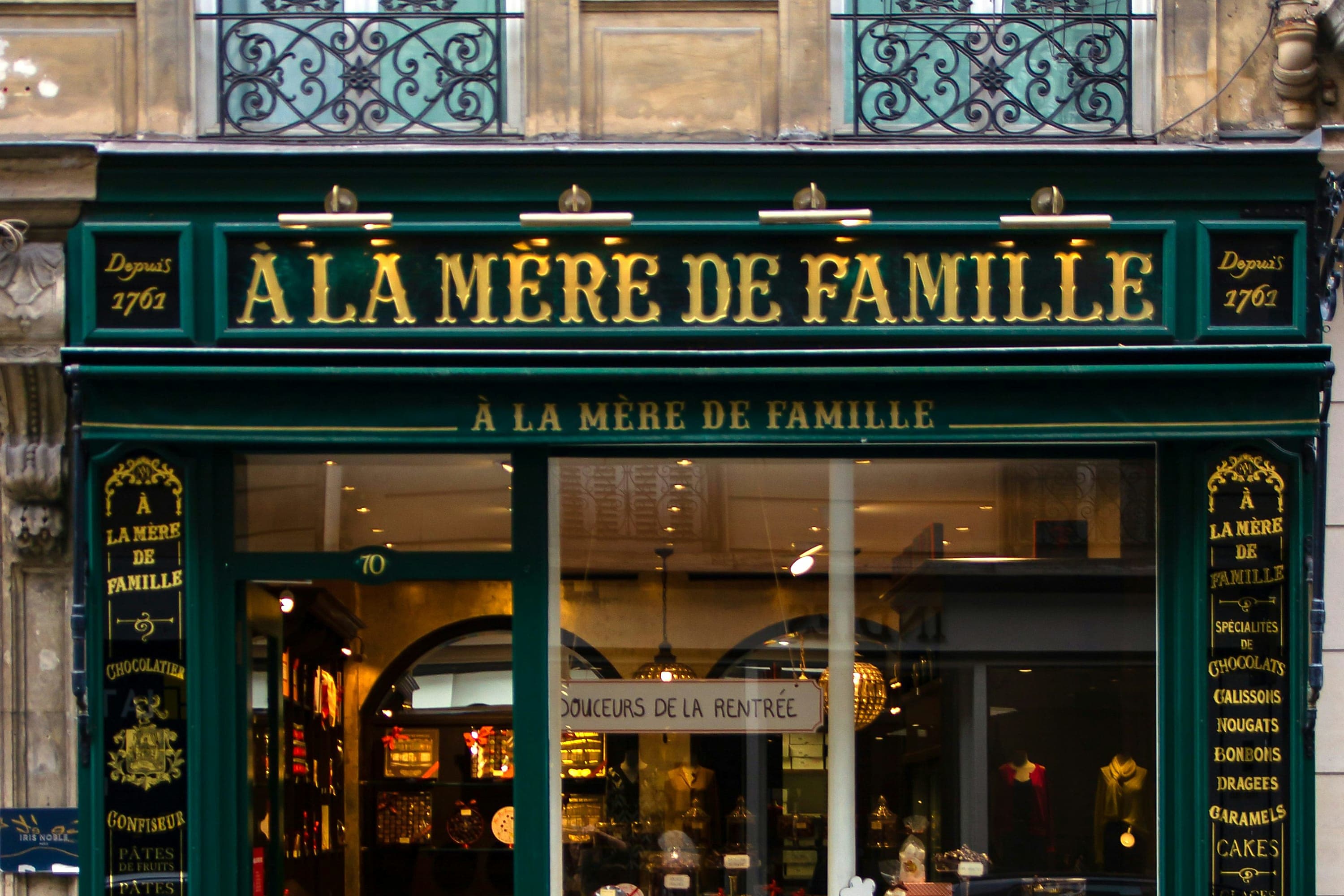 Up-close view of a Paris shopfront with a variety of local goods in the windows