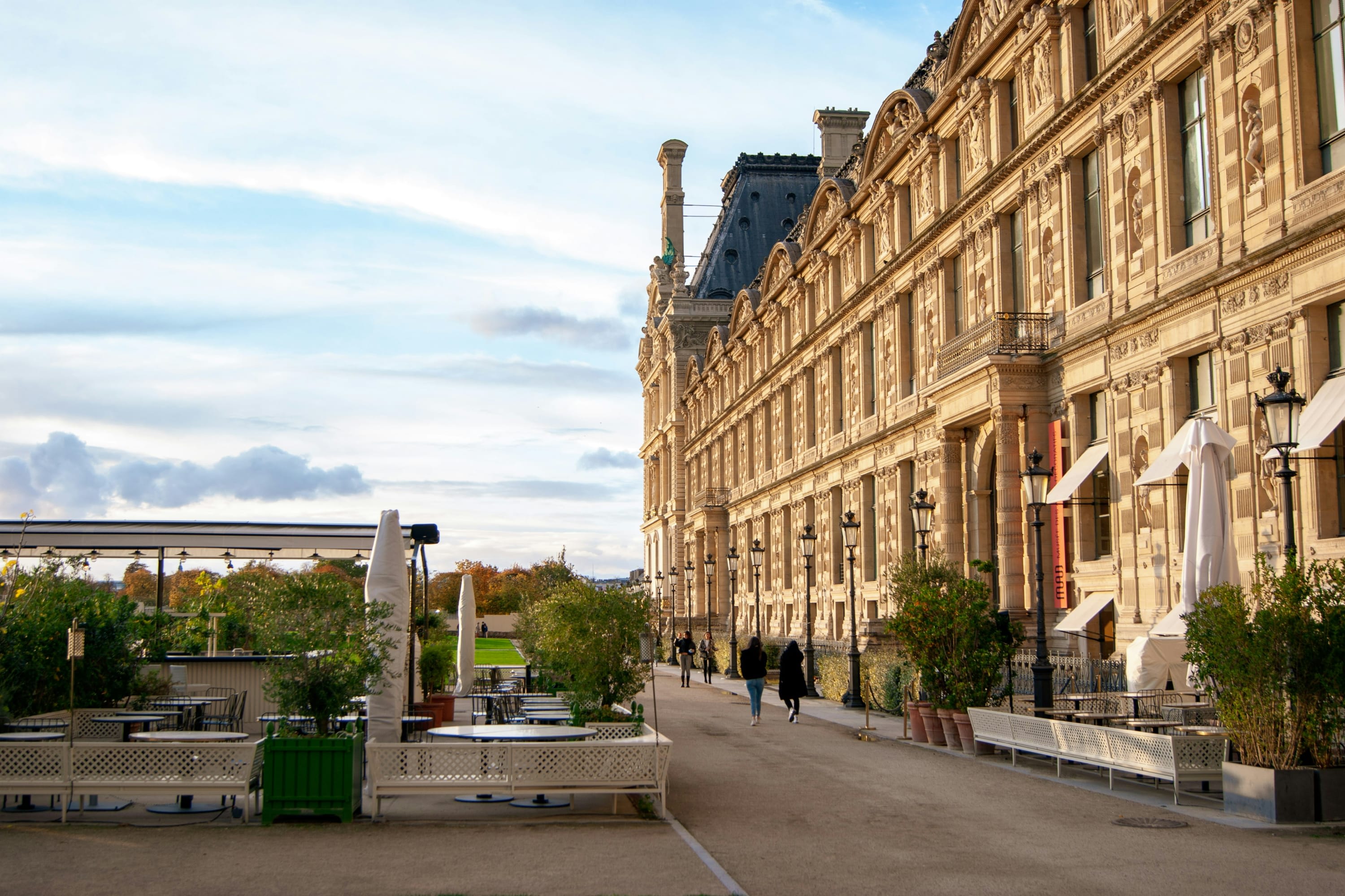 A small park and seating area next to the historic facade of a Paris museum