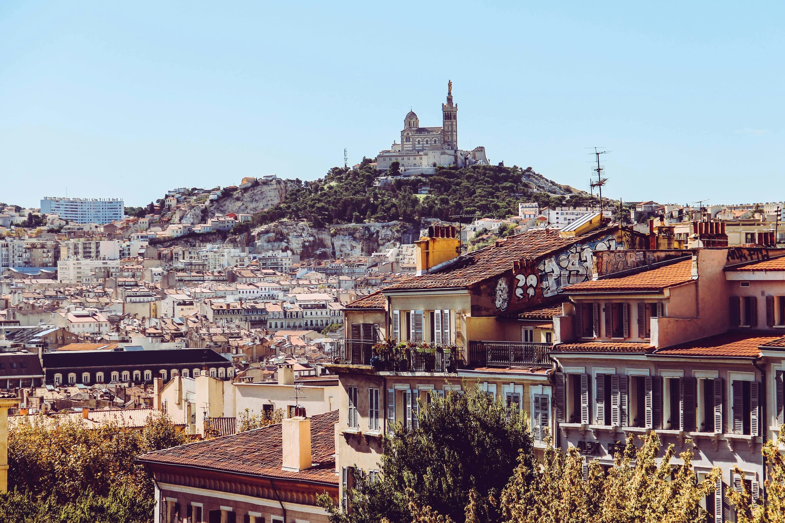 Historic buildings fill a hilly cityscape with an old fortress standing above the rest