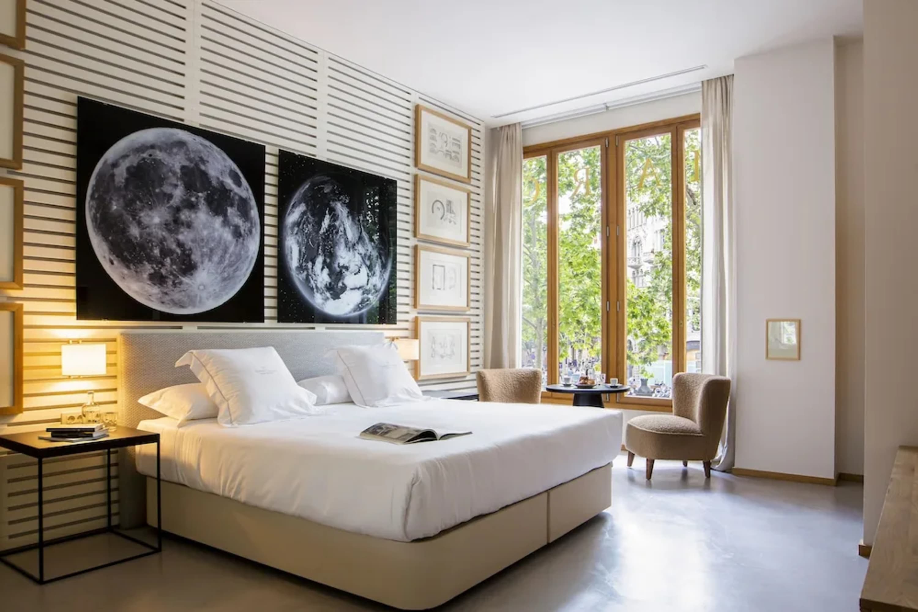 A spacious hotel room with bright natural lighting, science-themed art and a chic, contemporary vibe