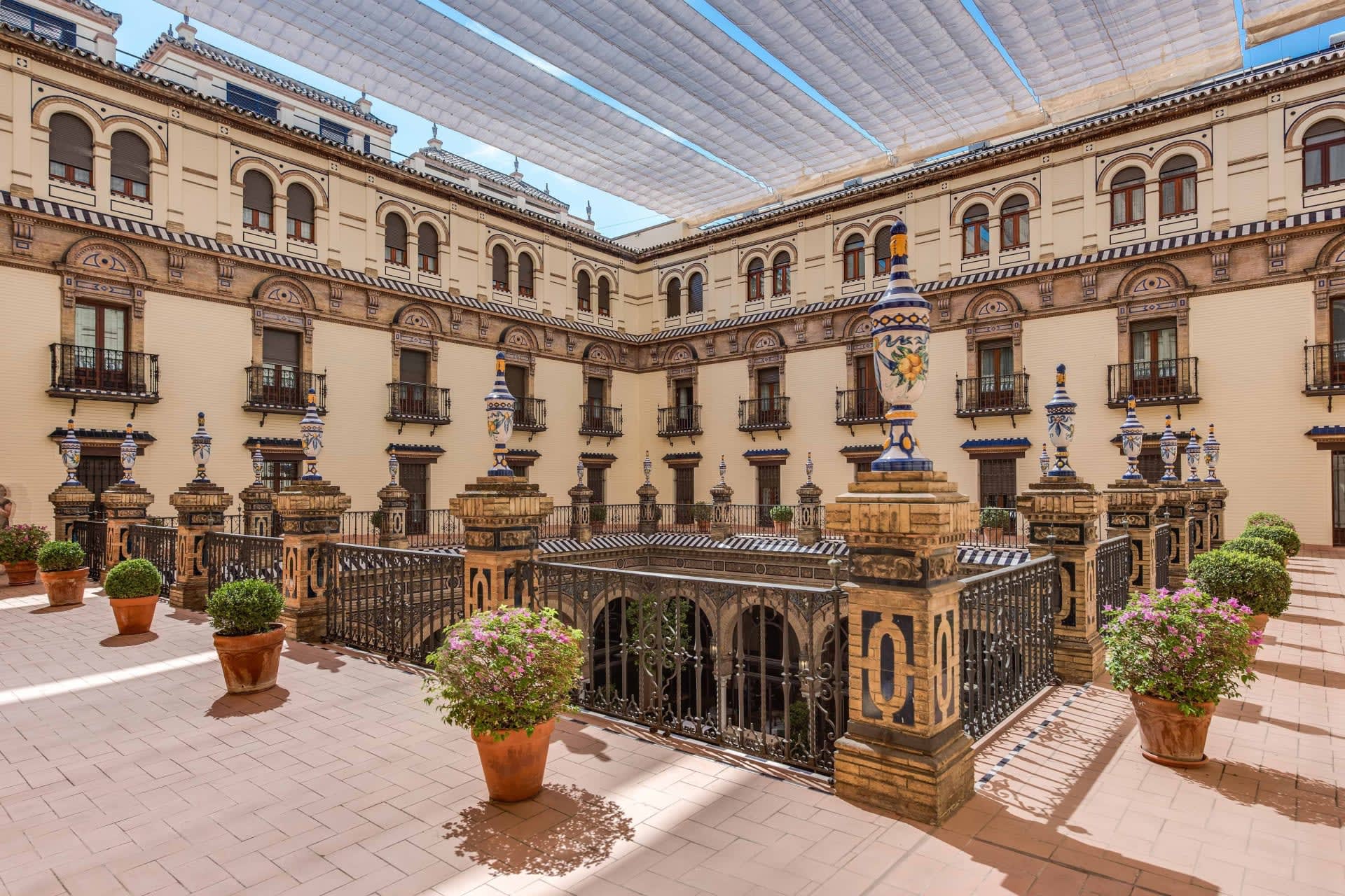 Elegant and spacious courtyard with historical wall faces, ornate railings and columns, and potted plants