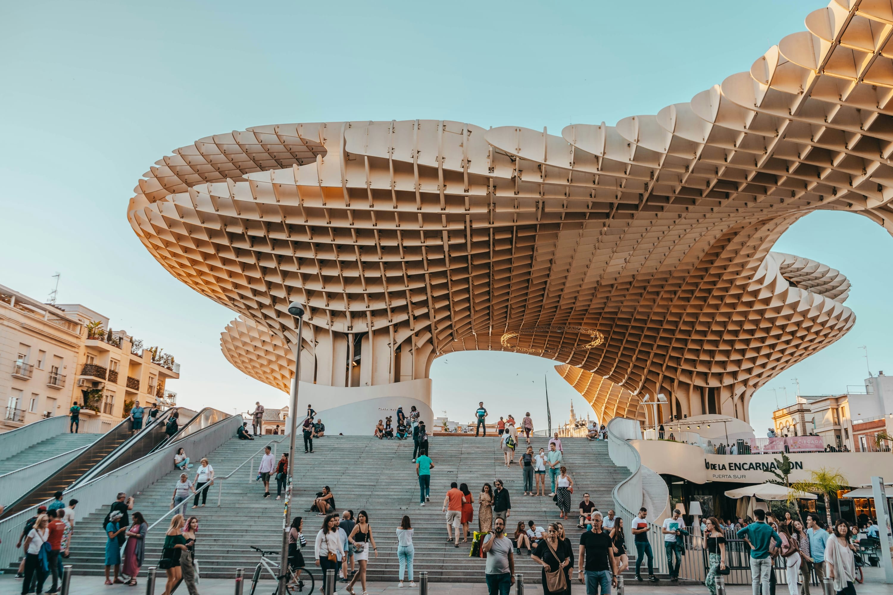 Abstract geometric architectural work in Seville surrounded by dozens of people on a busy plaza