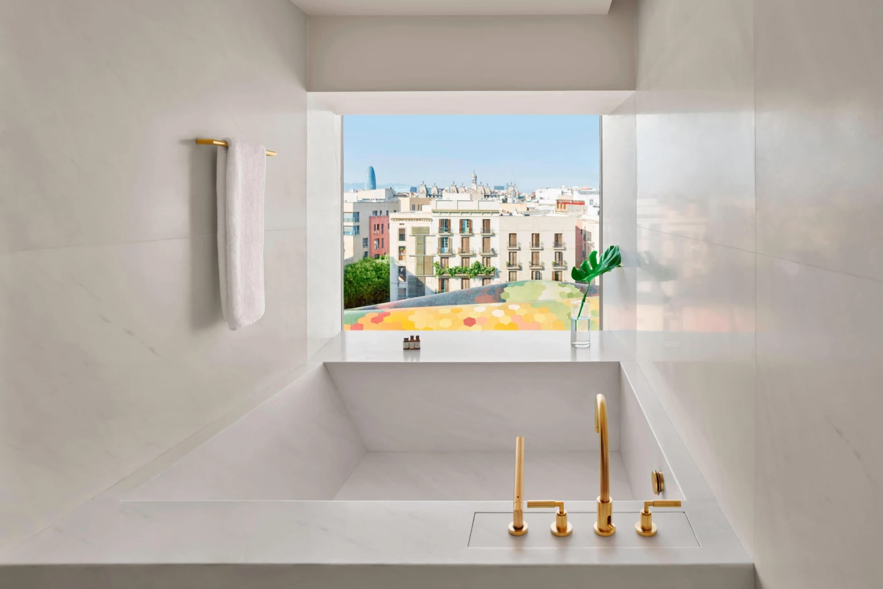 Ultra contemporary deep-soaking tub built into the surrounding room with a view of historic Barcelona