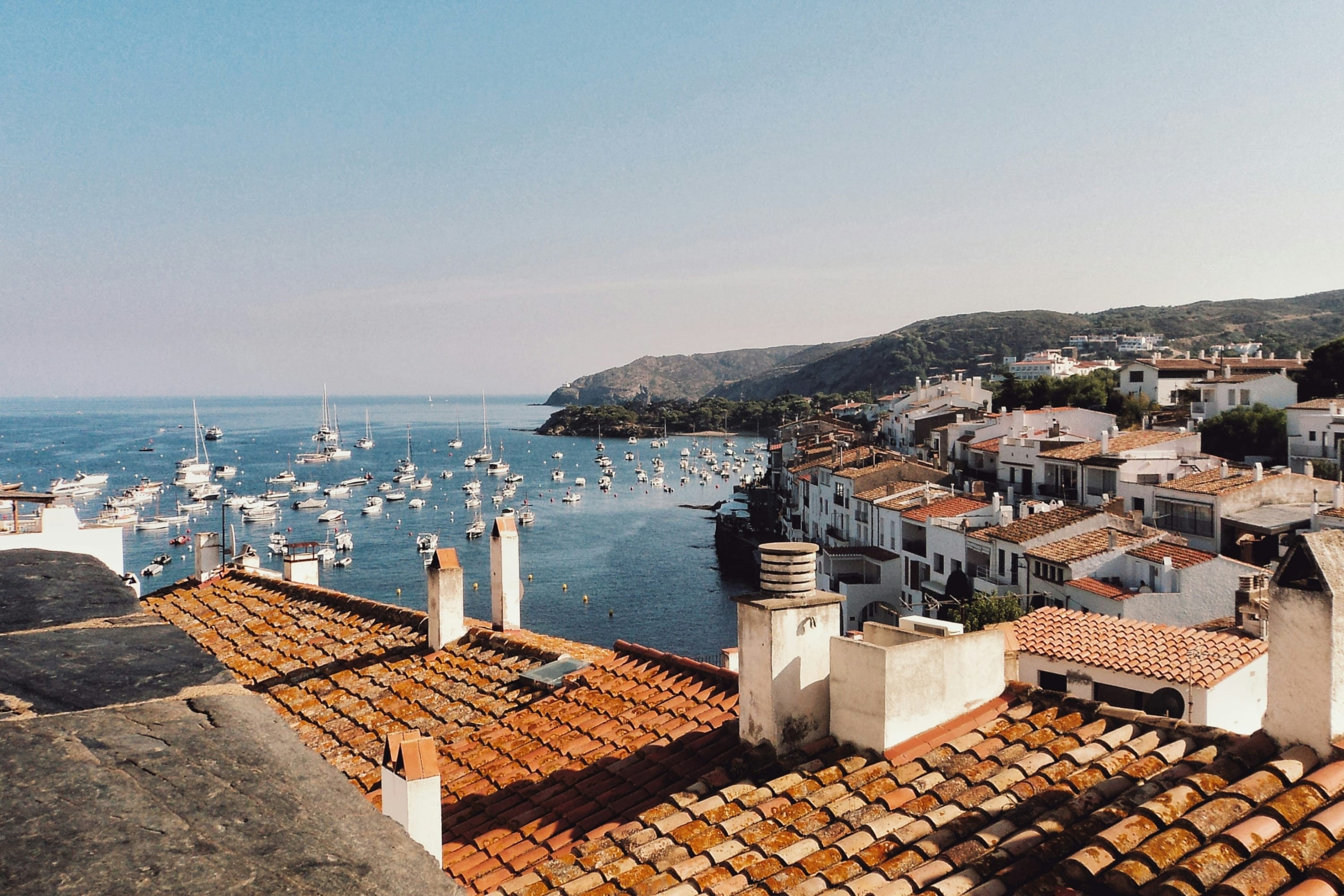 Orange tile roofs give way to a seemingly narrow harbor with tons of white sailboats