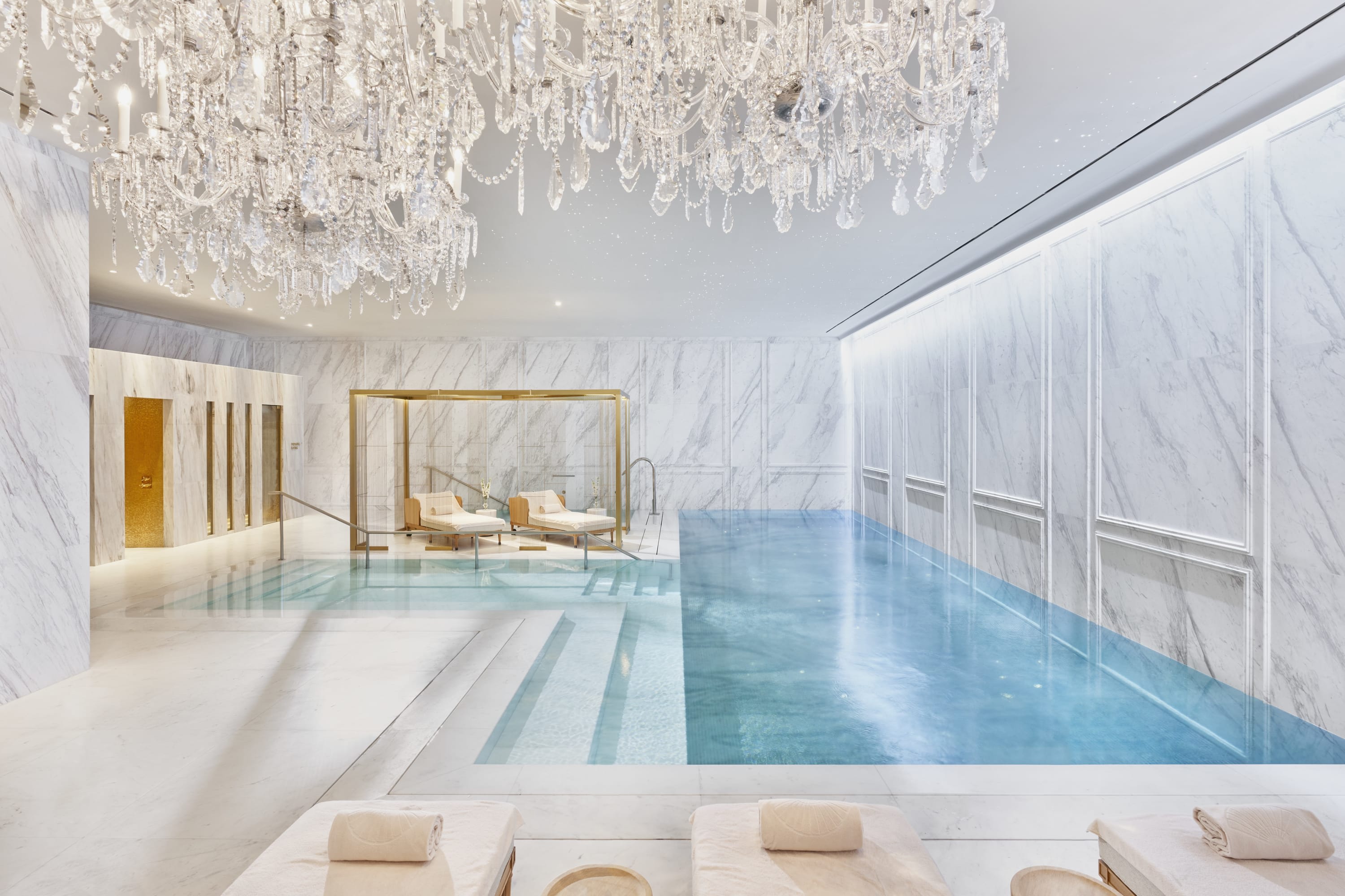 Luxurious pool area with crystal chandeliers, marble floors and turquoise water