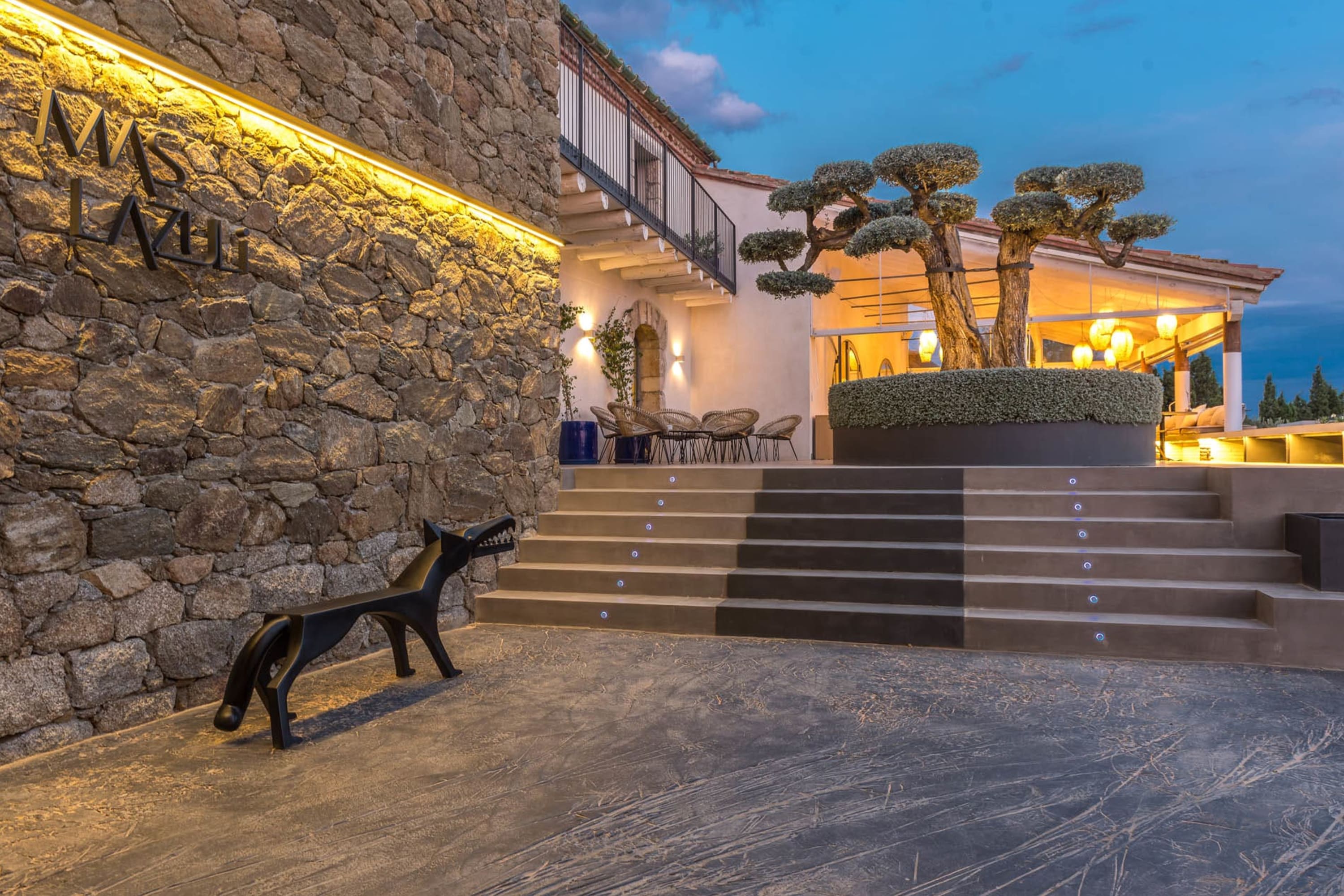 Chic and modern take on traditional architecture, with an abstract wolf sculpture and a tree trimmed in an unusual pattern