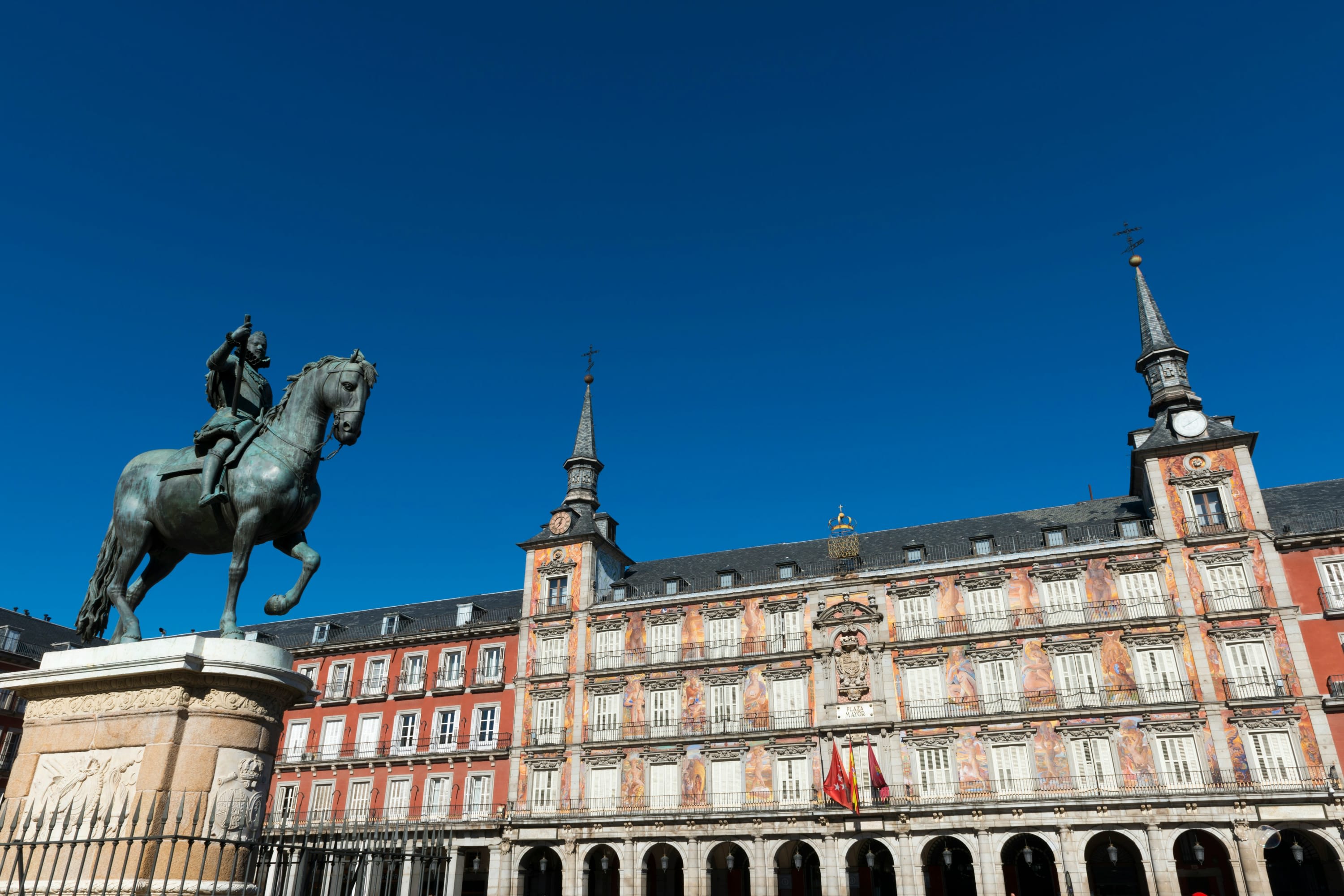 Bronze statue atop a large pedestal and backed by historic buildings