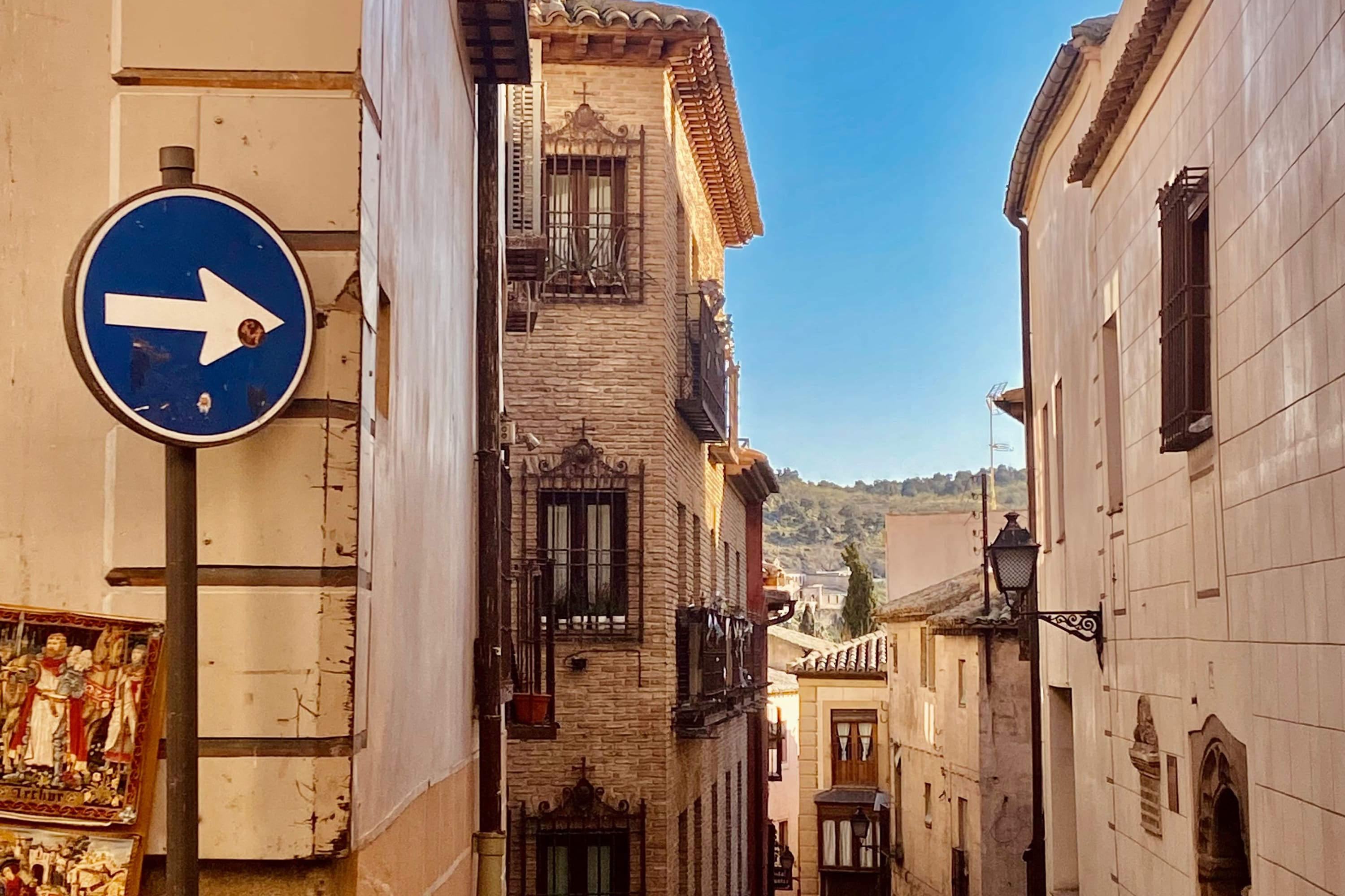 A street sign points down a historic street in Toledo, Spain on a sunny day