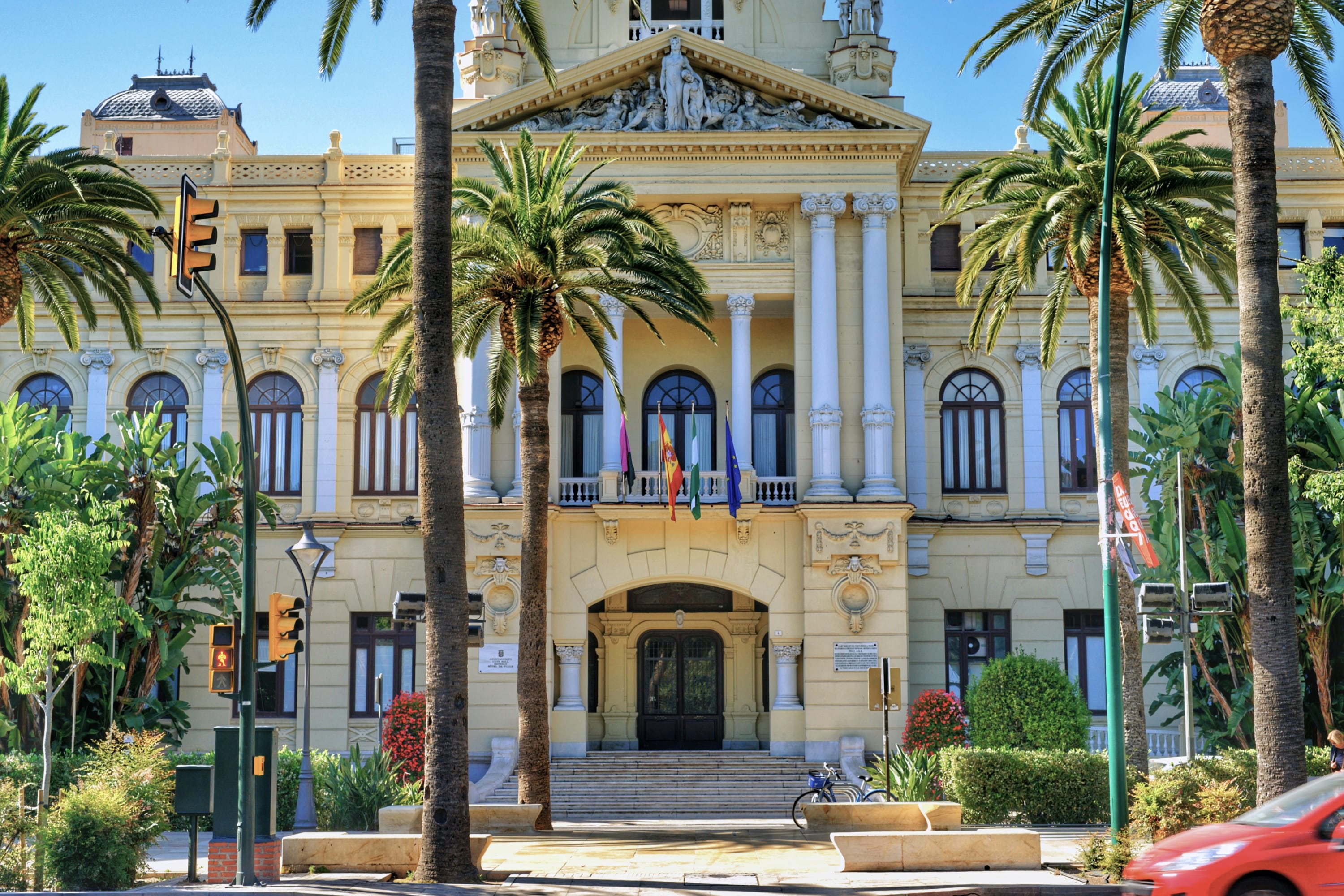 Palm trees in front of a historic building on a sunny day in Málaga, Spain