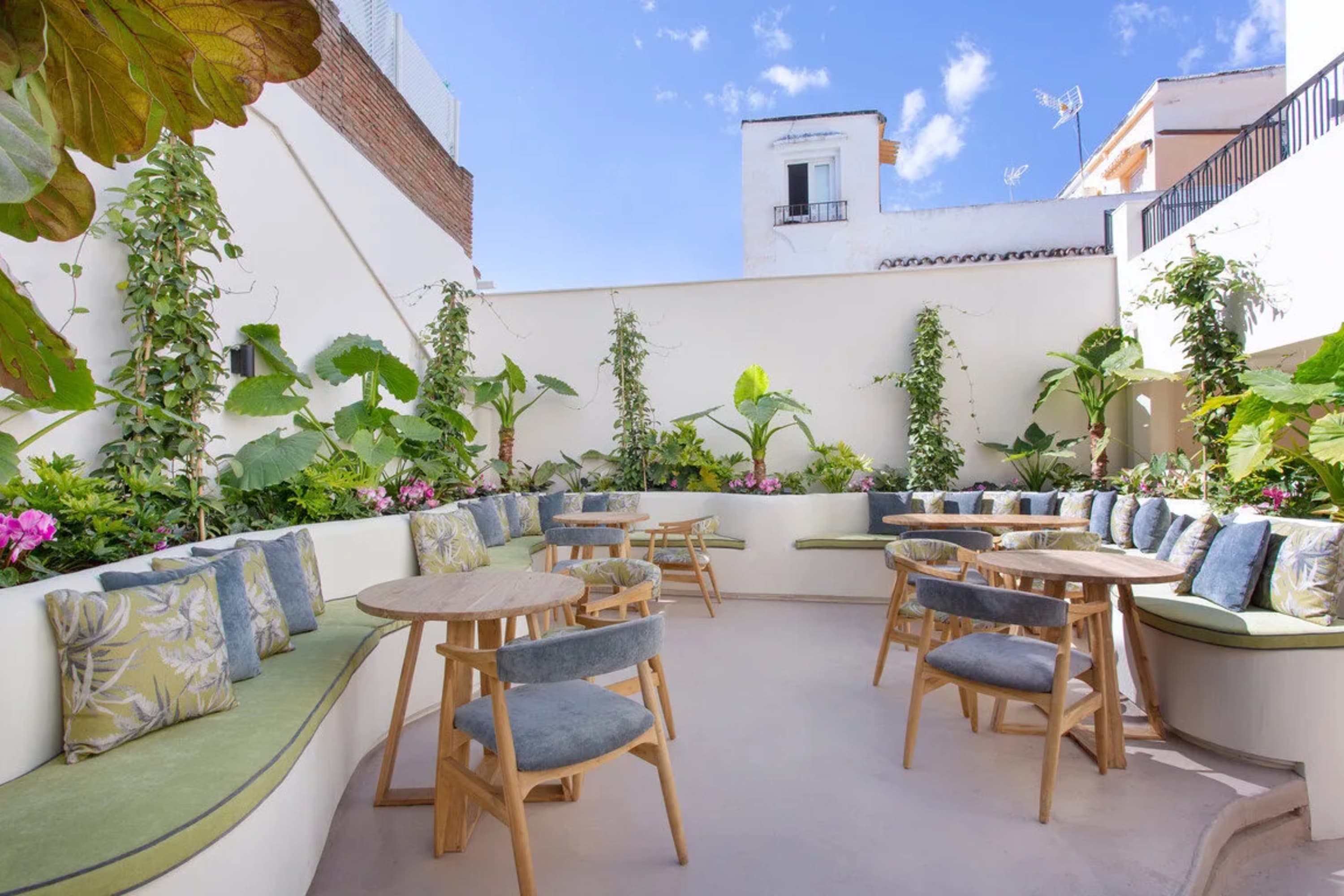 A chic outdoor space with tables, outdoor sofas and gardens on a sunny day