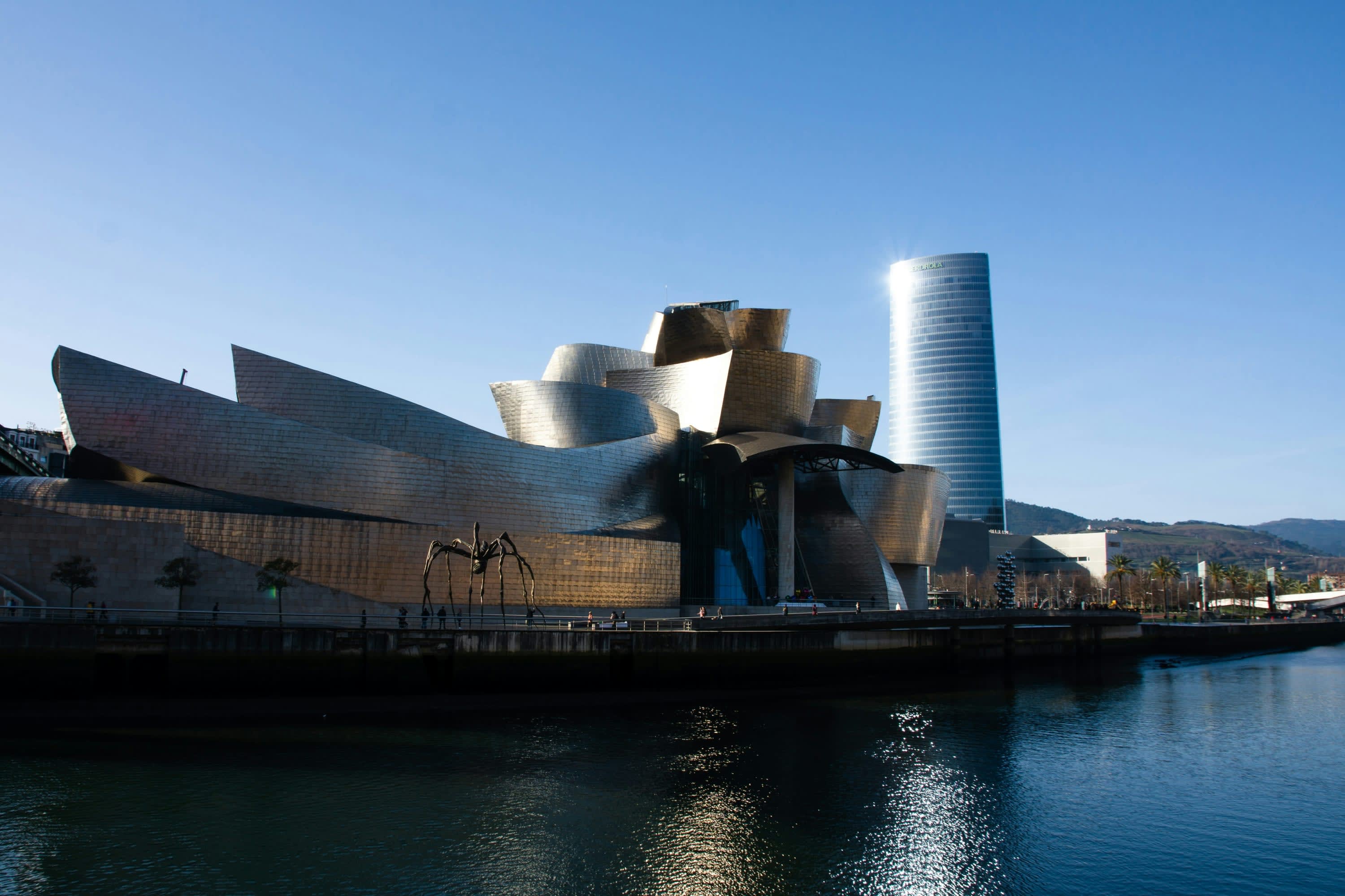 Abstract metal building with an unusual spider statue out front and a canal