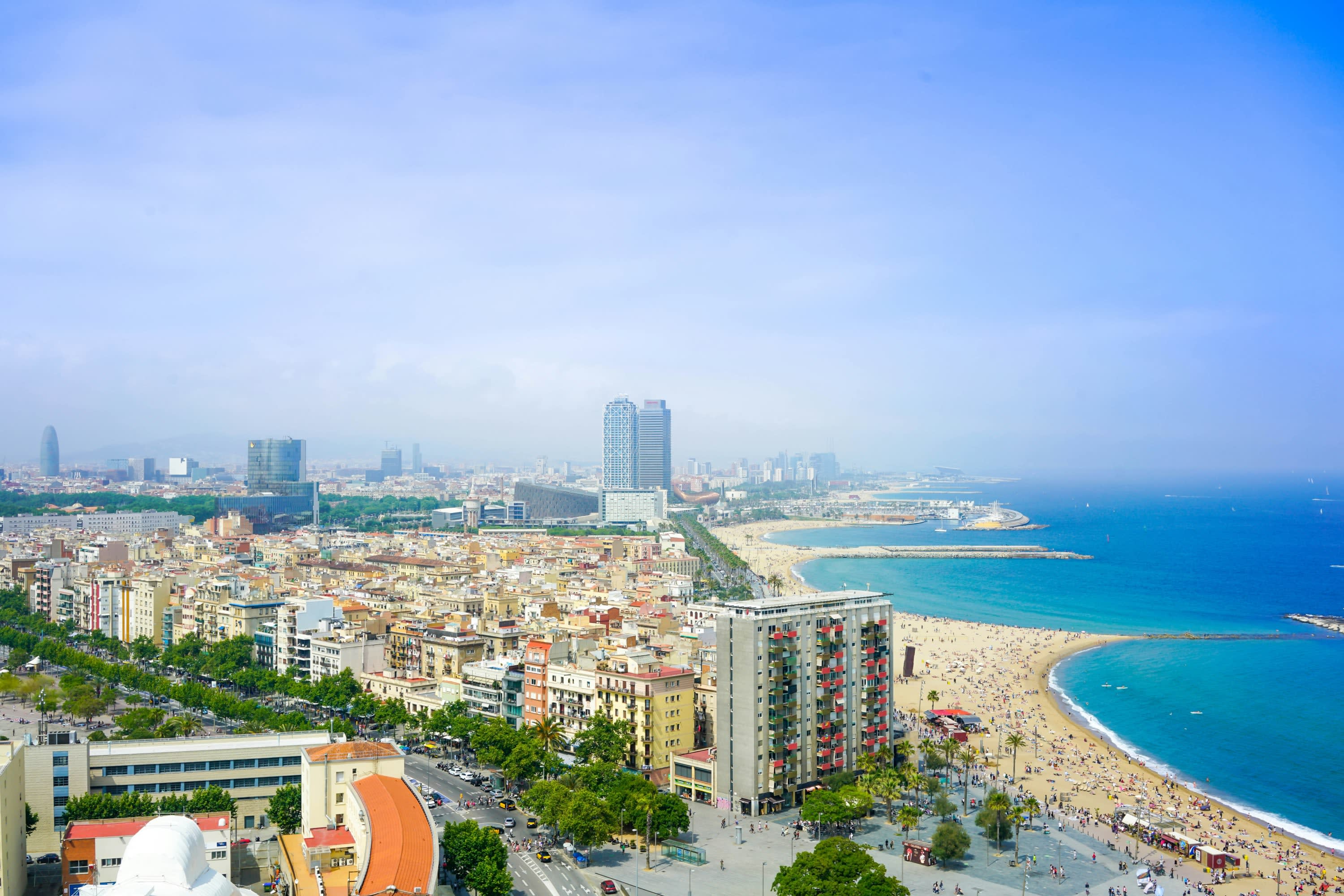Aerial view of the beach and a historic neighborhood in Barcelona on a mostly sunny day