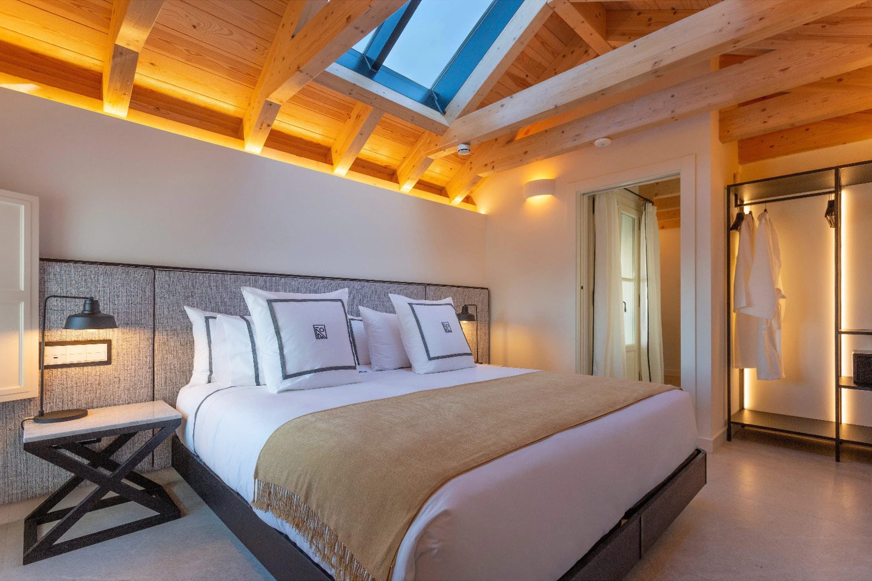 Chic hotel room with modern furniture and a contemporary vaulted wooden ceiling with a skylight