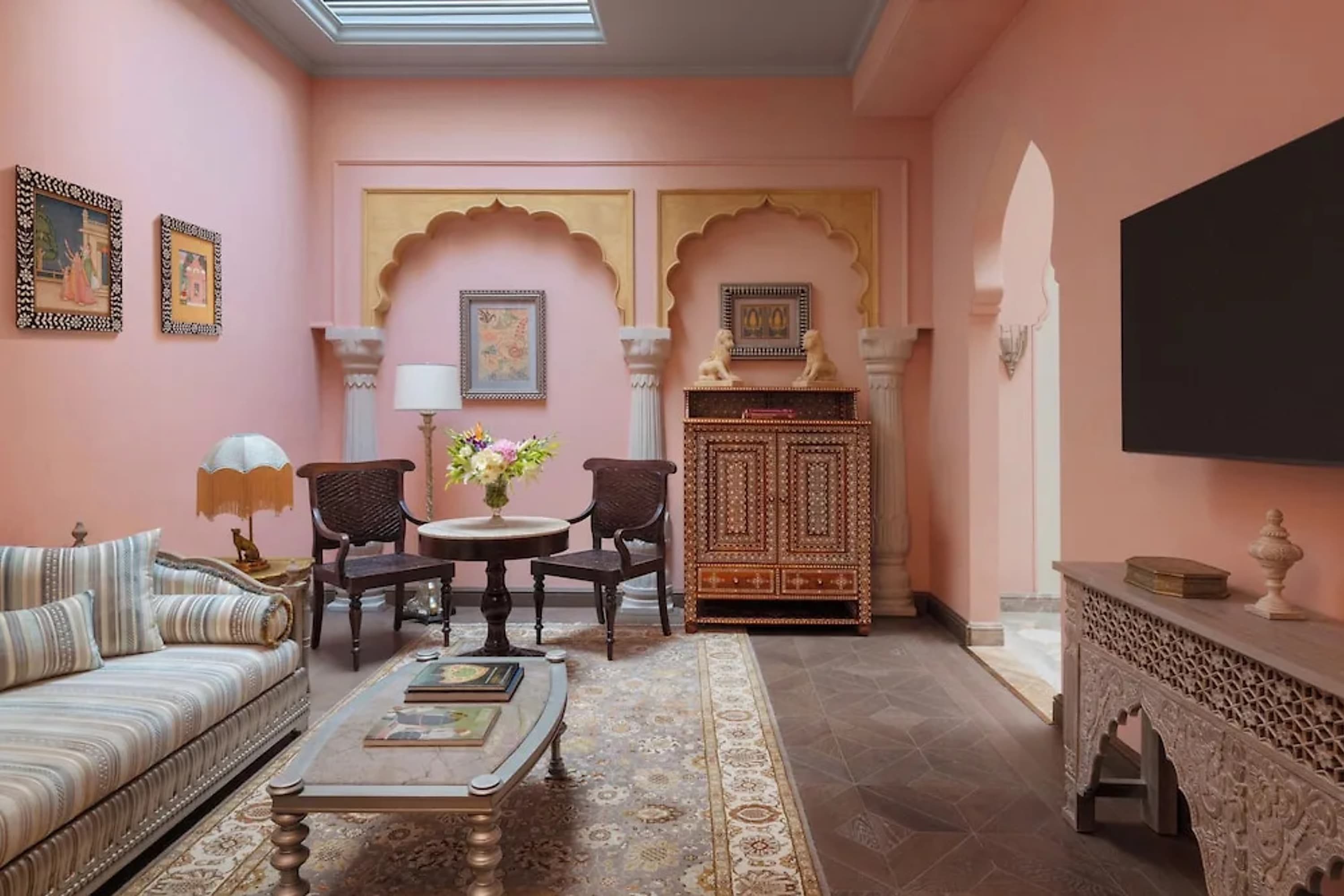 Elegant hotel suite living room with pastel pink walls, local art and extravagant upholstery on the furniture